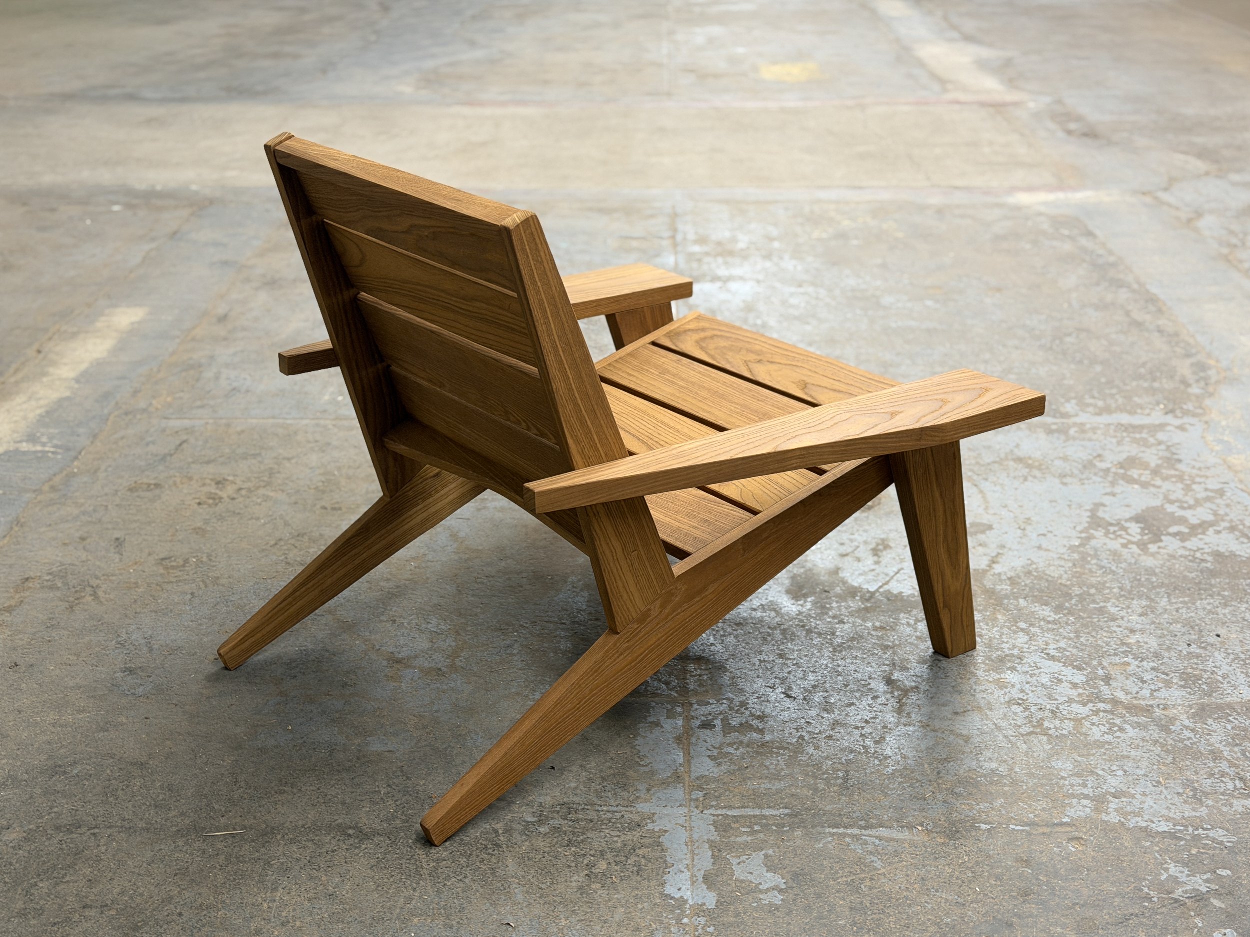 A wooden chair with armrests placed on a stone or concrete floor.