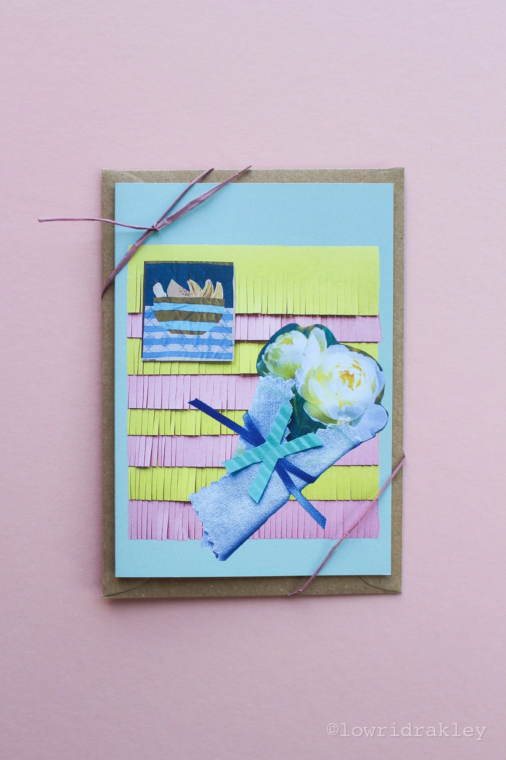 Handmade mixed-media art card titled "The Banana Fruit Bowl & Bouquet," featuring a playful fruit bowl illustration, white flower bouguet, and yellow and pink fringe on a blue background.