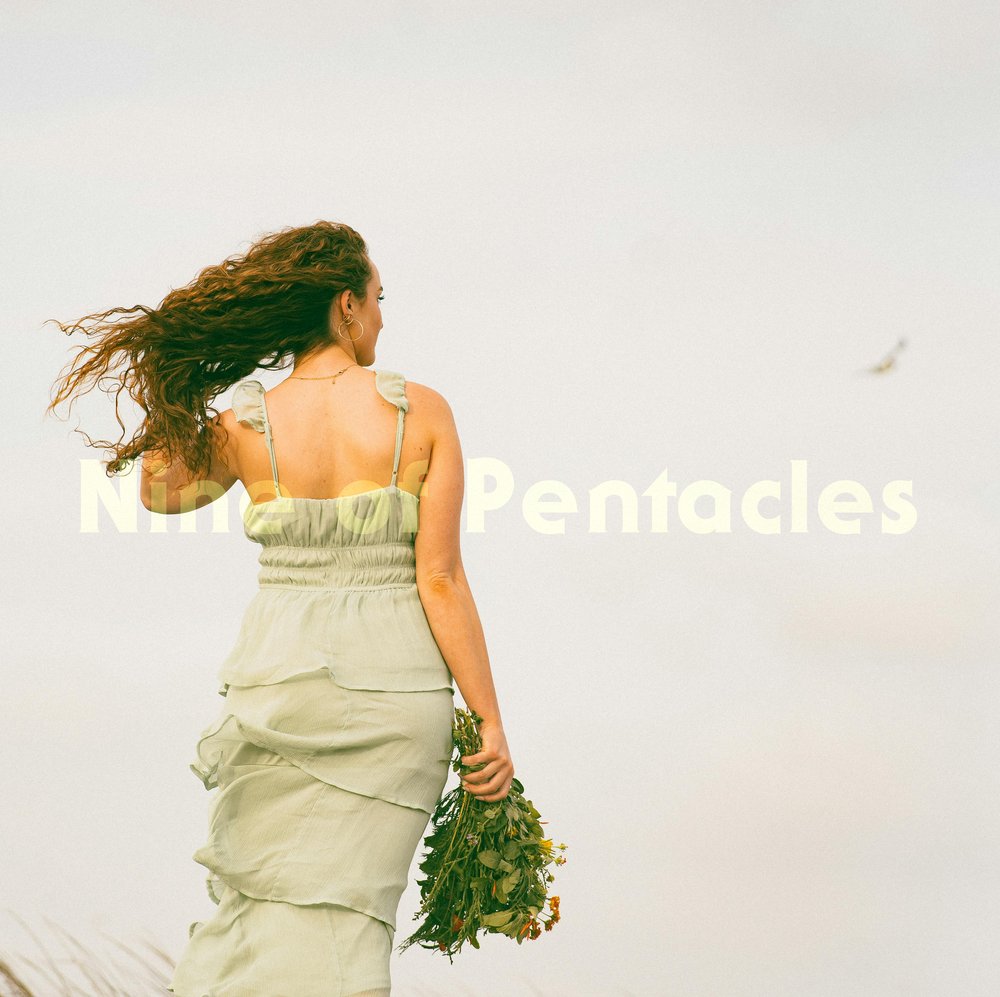 A woman in a pale green dress walks forward, holding a bouquet of greens. The sky behind her is soft and pale. She walks alone, unhurried. A single bird flies in the distance.