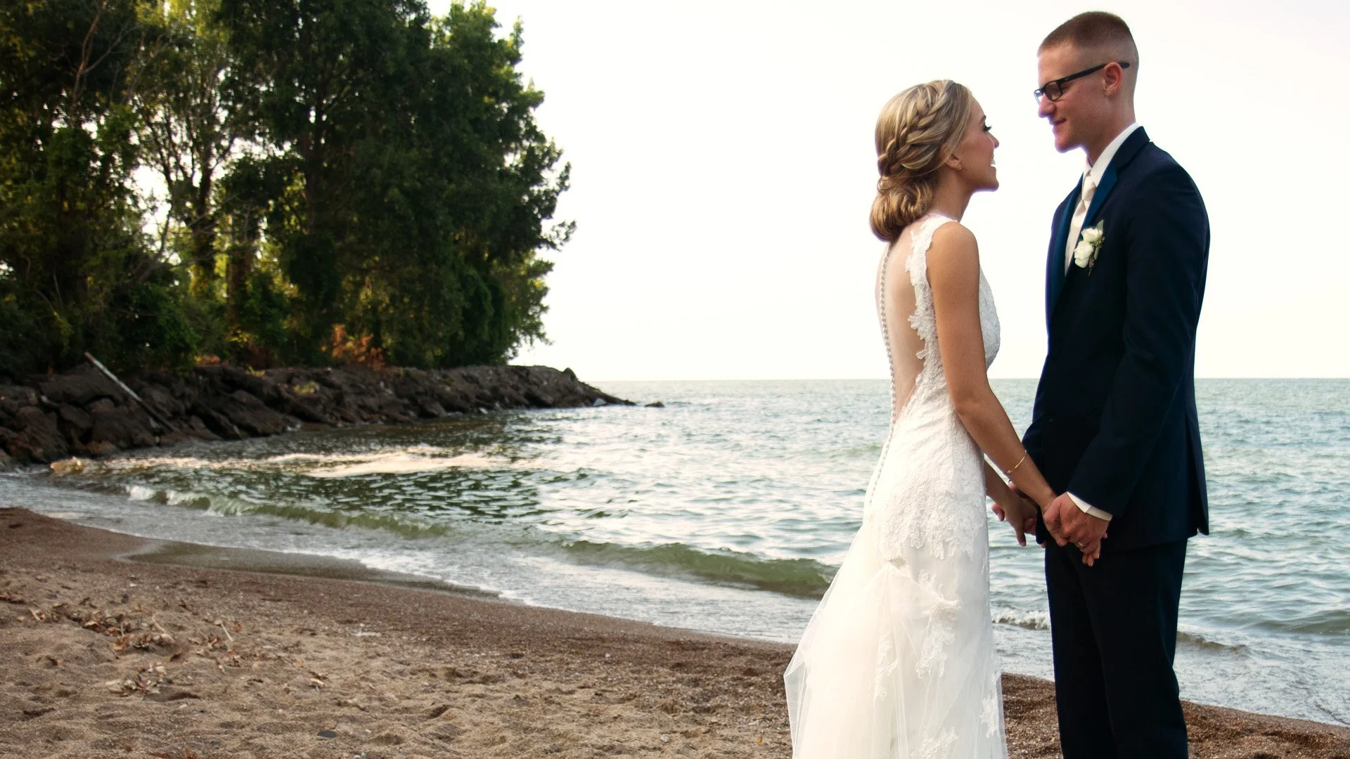 Cinematic wedding film still of a couple on a Lake Erie beach in Sandusky, Ohio, featuring waterfront views near the islands.
