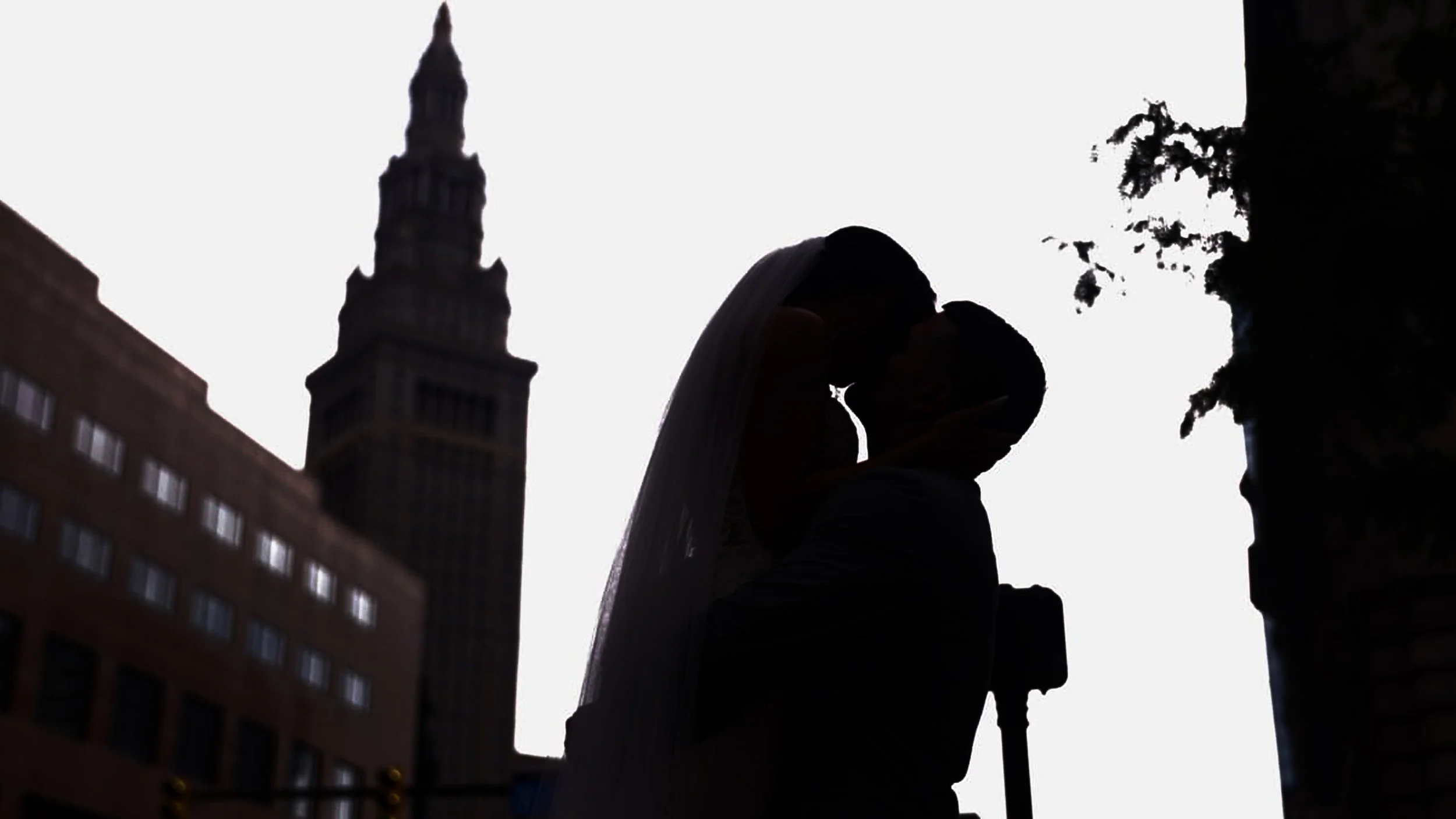 Silhouette of a newlywed couple, kissing in Cleveland, Ohio with Tower City in the background.