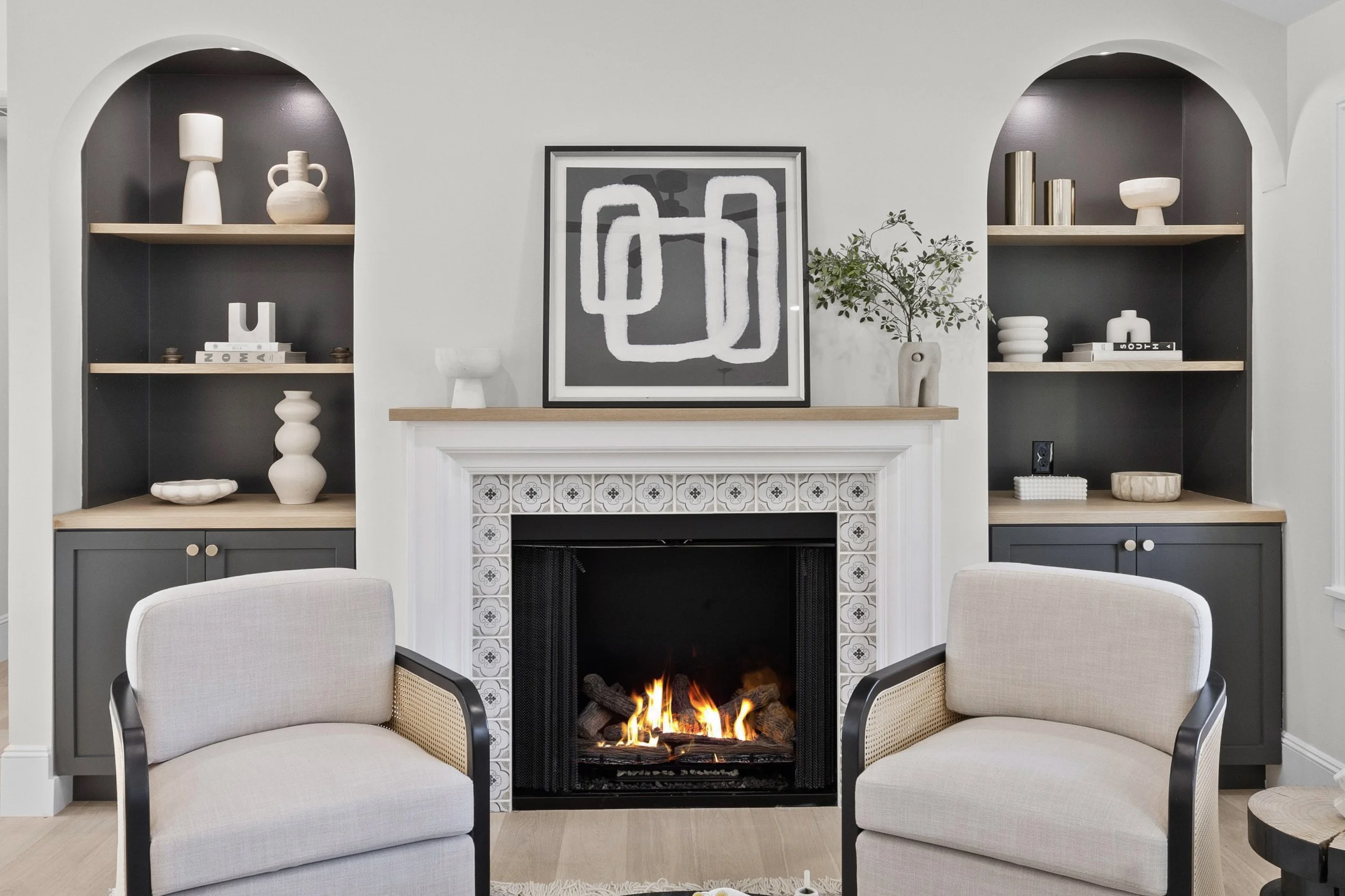 Living room with a fireplace, two beige armchairs, and built-in shelves with decorative items.