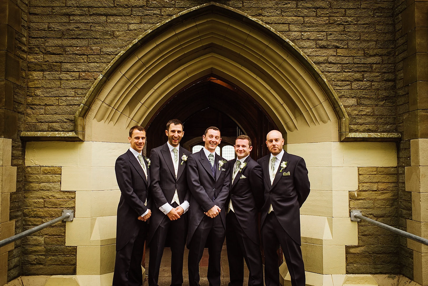 Five grooms men stood outside a church doorframe