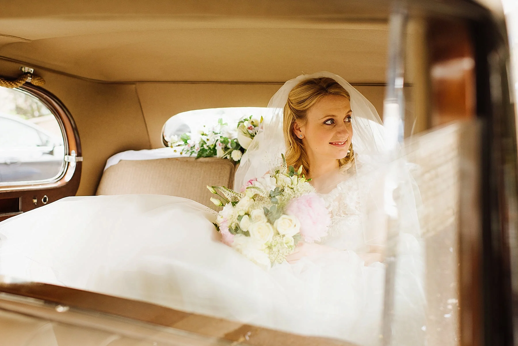 bride sat in car with wedding flowers