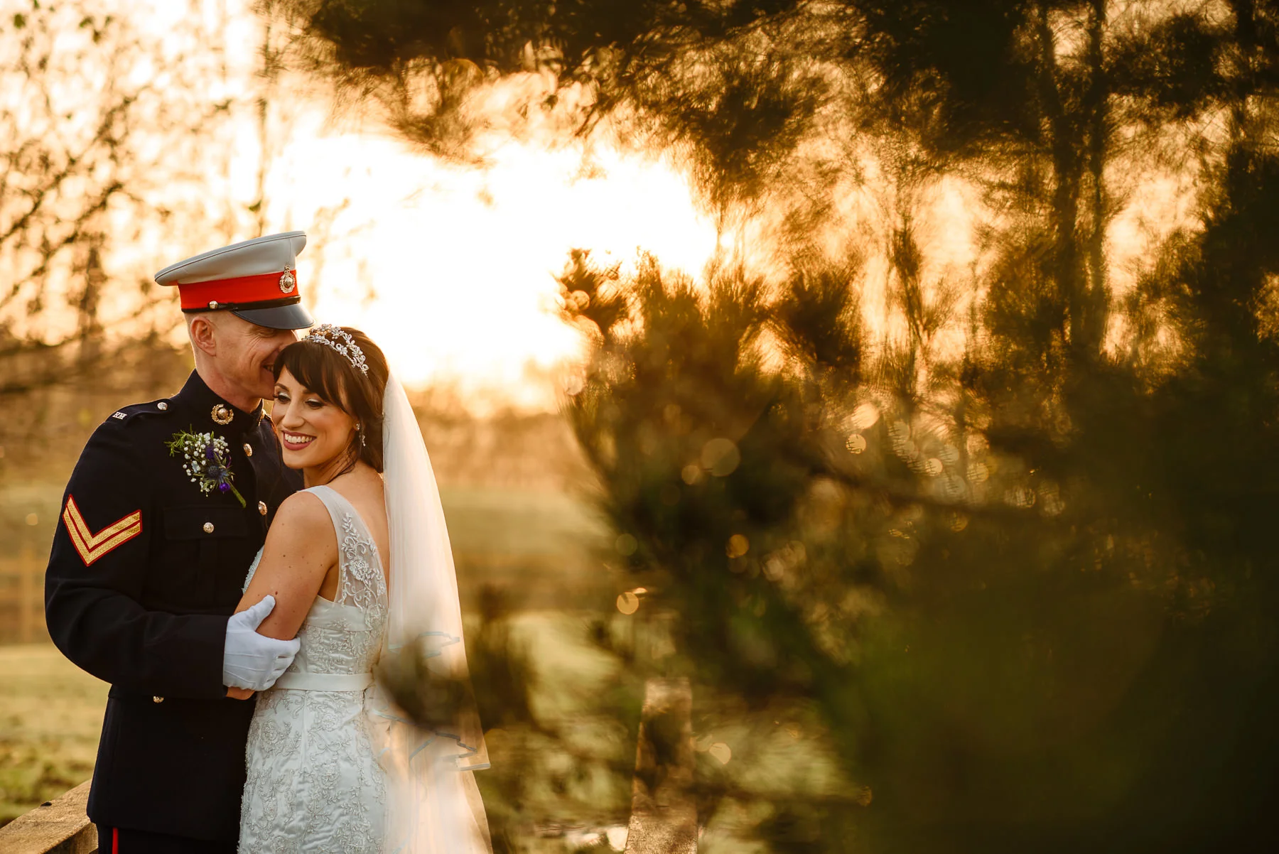 Military groom cuddling his bride at Charnock Farm near Leyland at sunset