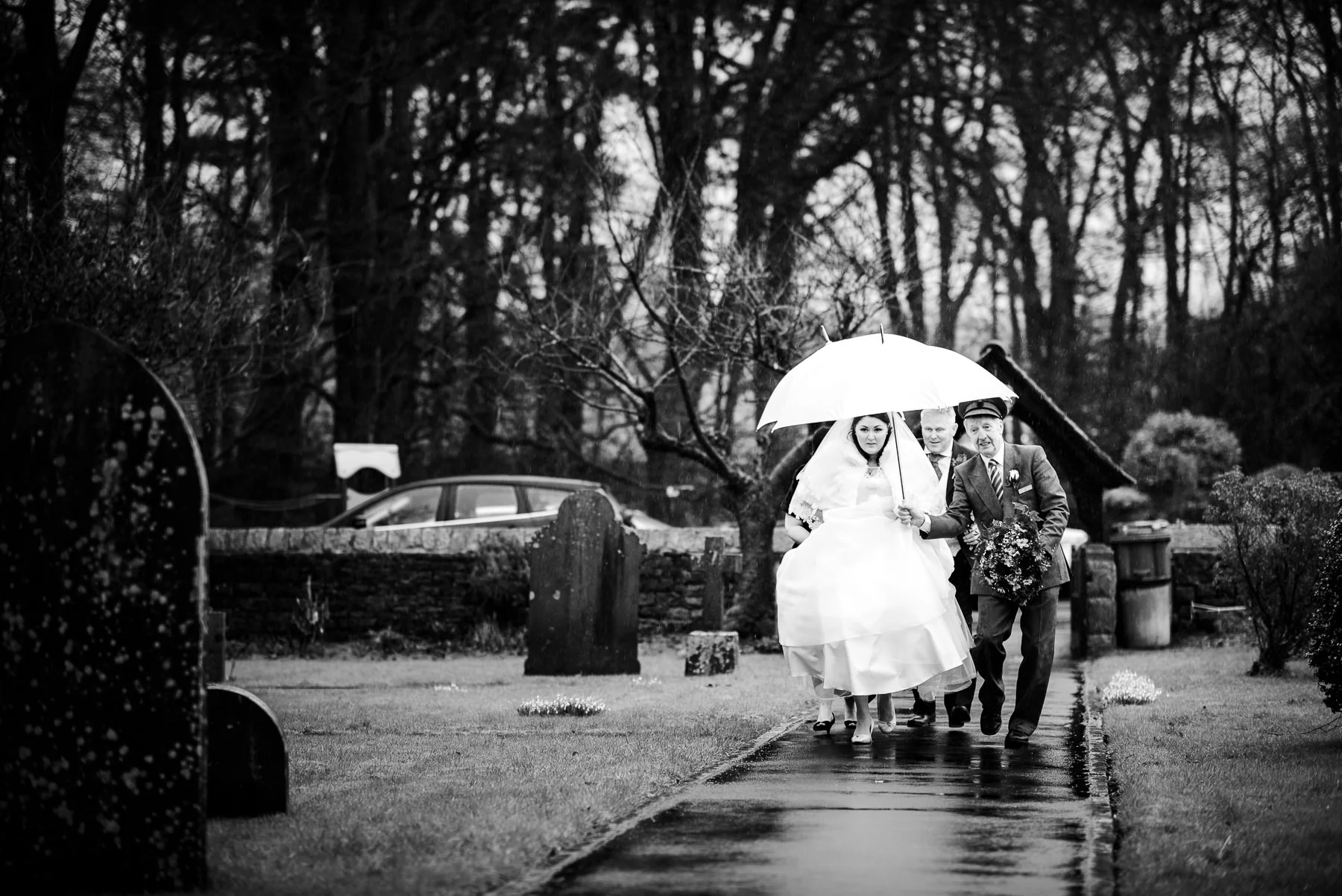 Donna walking towards the church on a rainy english wedding day