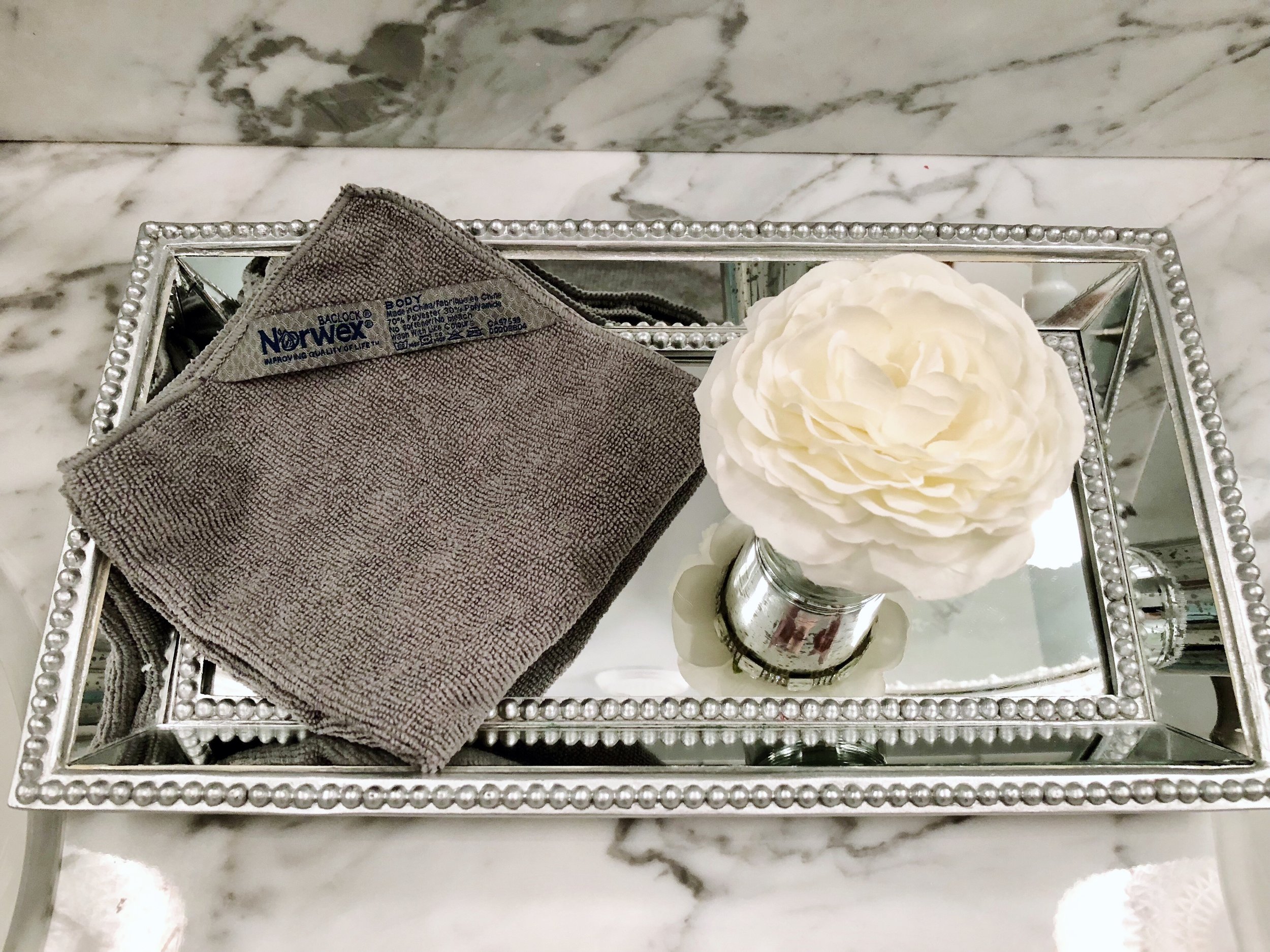 norwex body cloth on pretty mirrored tray in marble bathroom.JPG