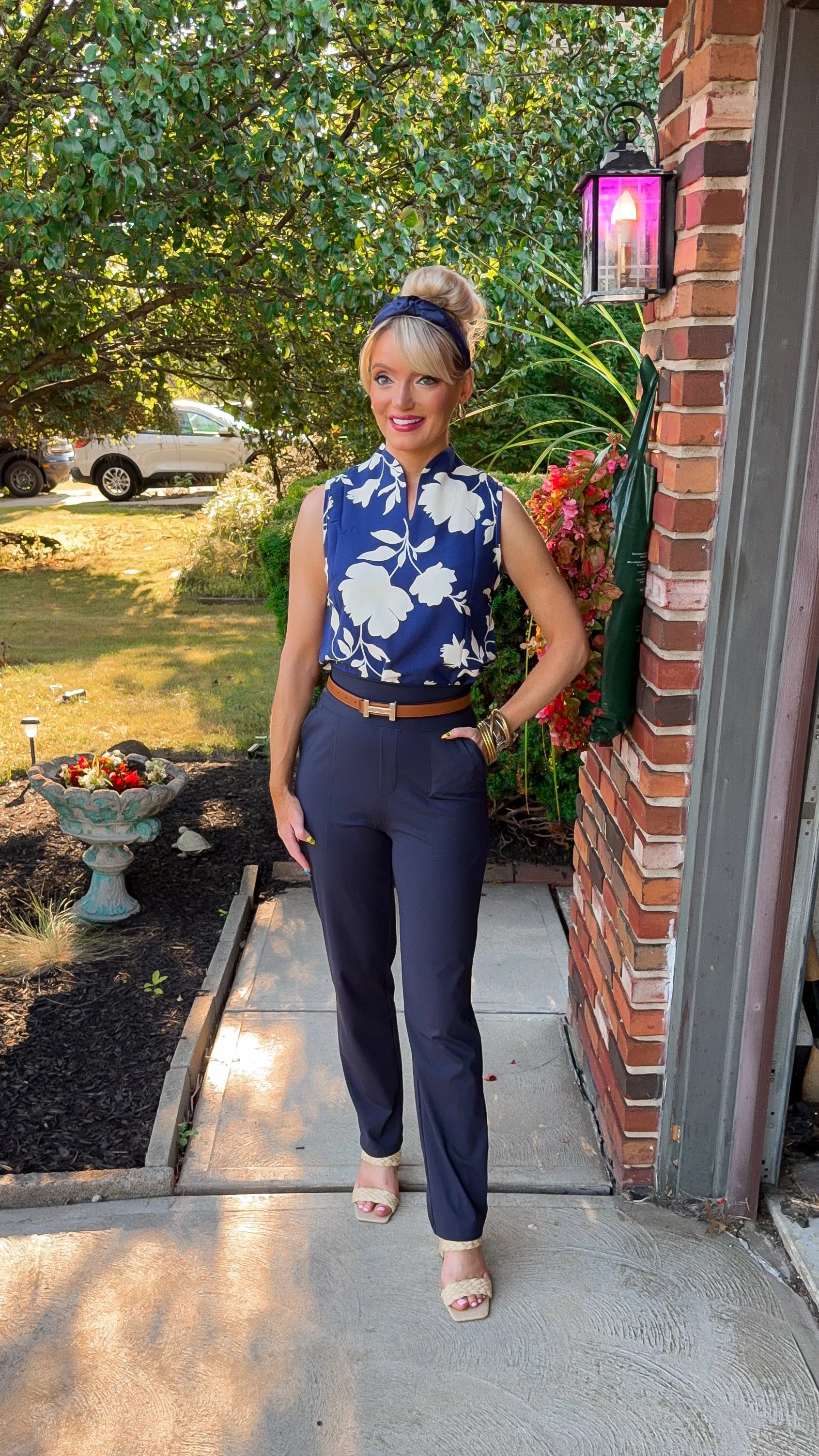  Blonde woman wearing business casual look for late summer into early fall with deep navy blue tones with a floral sleeveless top and navy blue Dress pants and look for less accessories from Amazon  