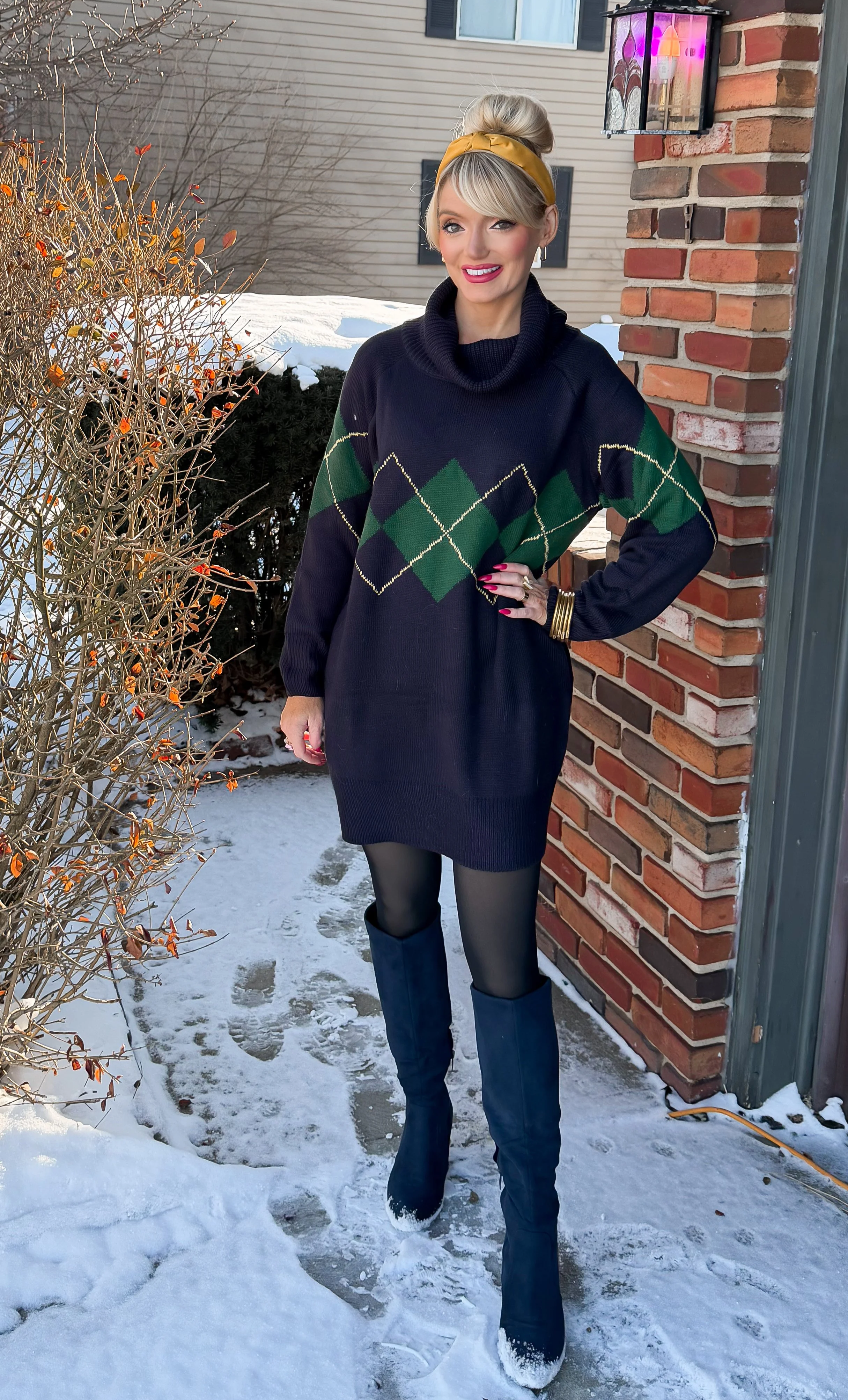 Blonde woman with top knot wearing chunky argyle knit sweater dress from Amazon with knee high boots in snow