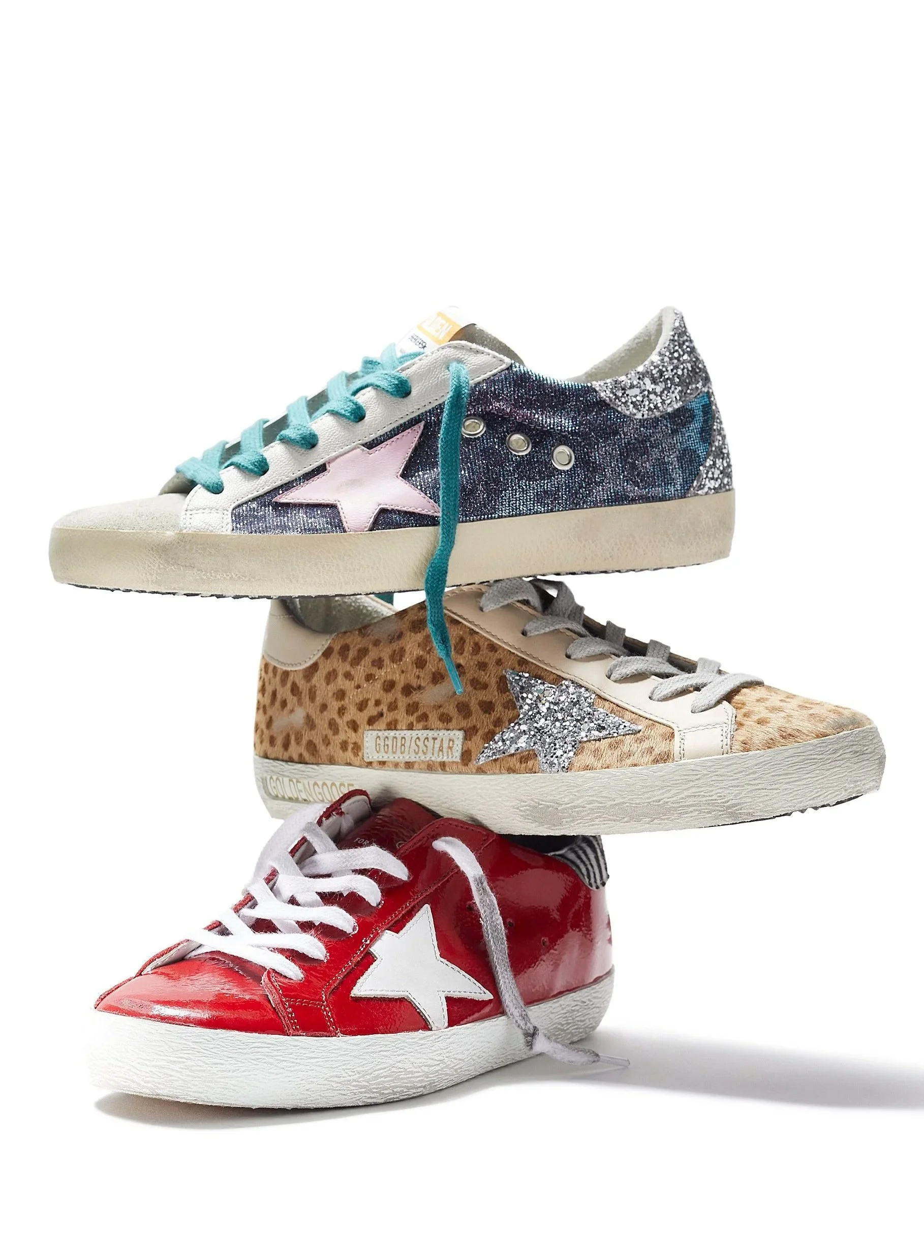 A stack of four colorful sneakers featuring various designs and embellishments, including glitter, stars, and animal print.