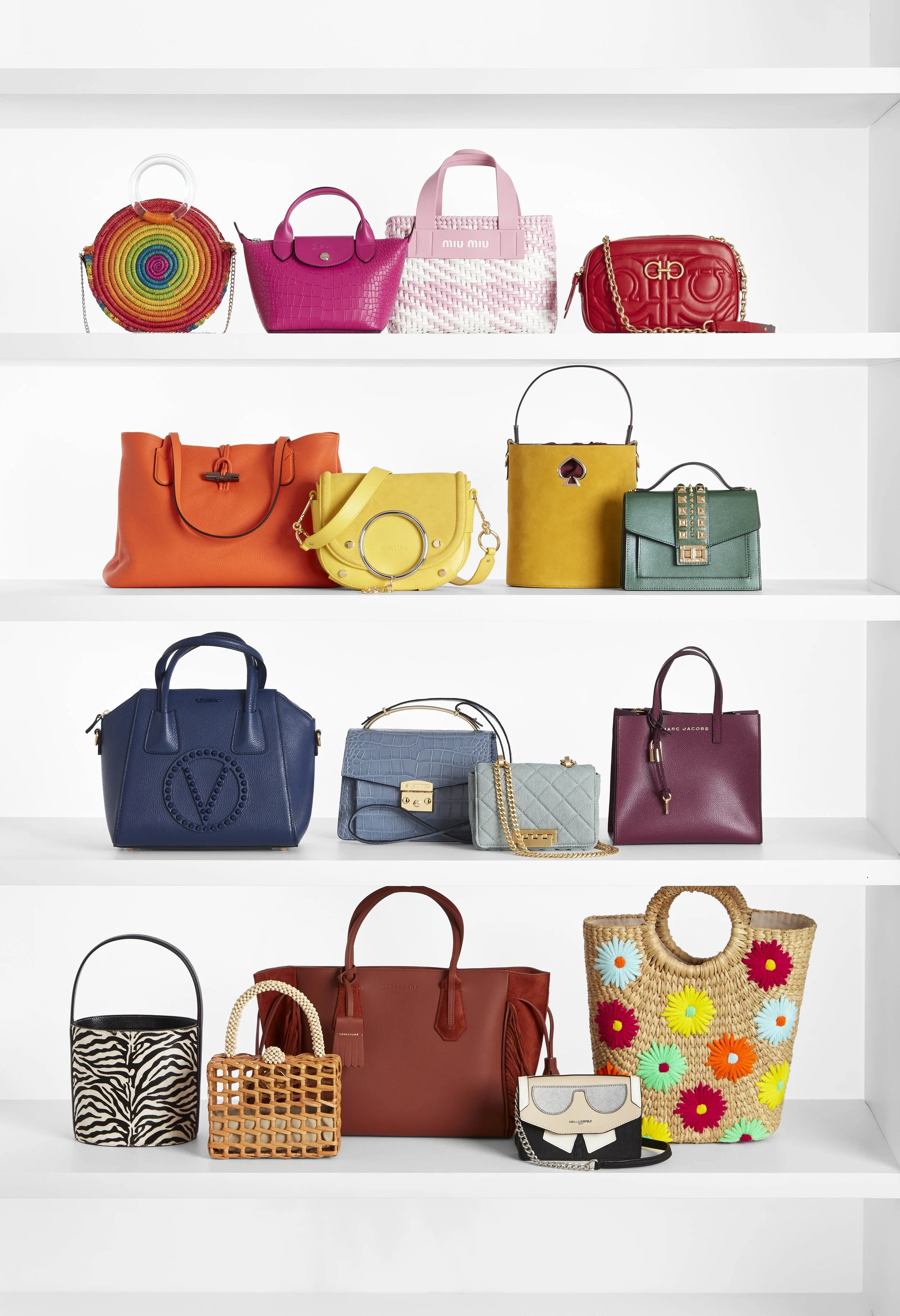 A collection of colorful designer handbags and purses displayed on white shelves.