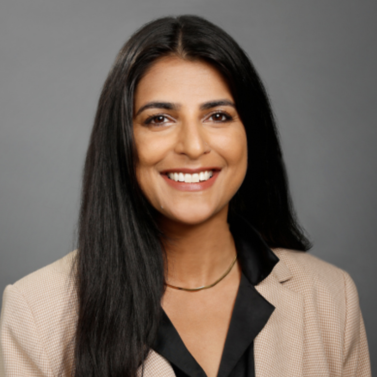 Smeeta Singh smiling at the camera i a tan blazer and black shirt