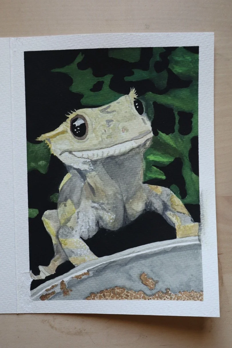 sample work watercolor painting with a green background and an image of a pale yellow lizard