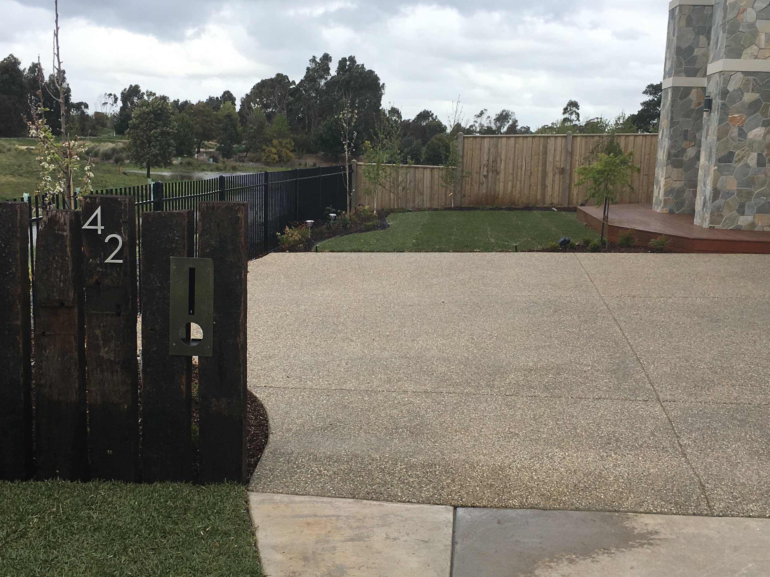 Instant turf, garden bed and old sleeper upright staggered fence with letter box