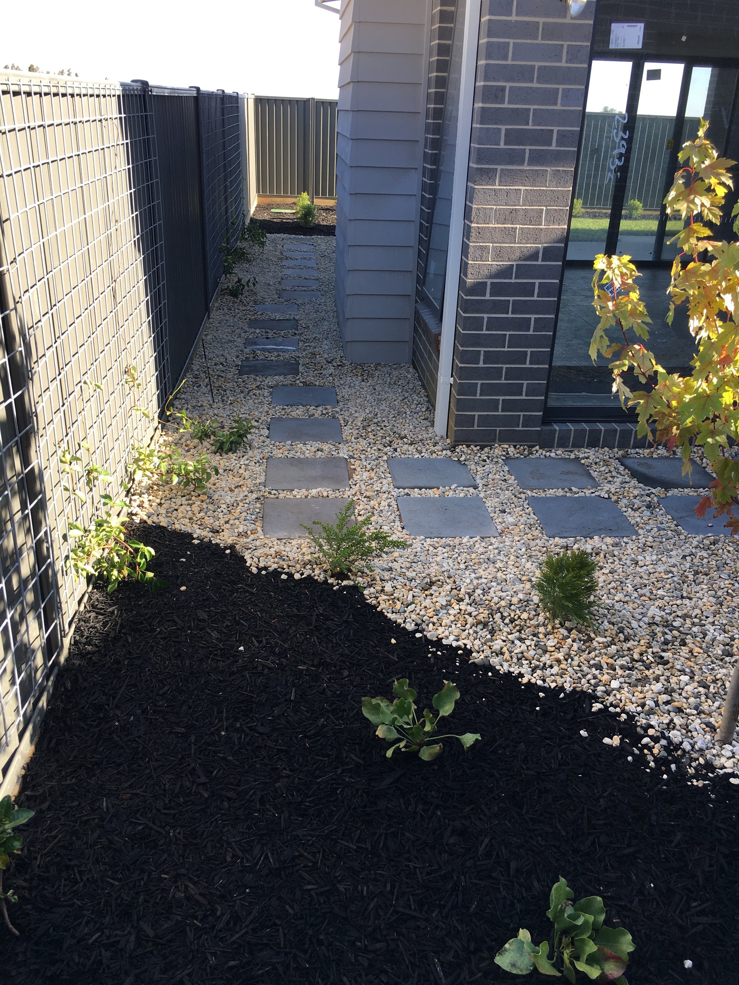 Garden bed with black mulch and pebble mulch with stepping pavers