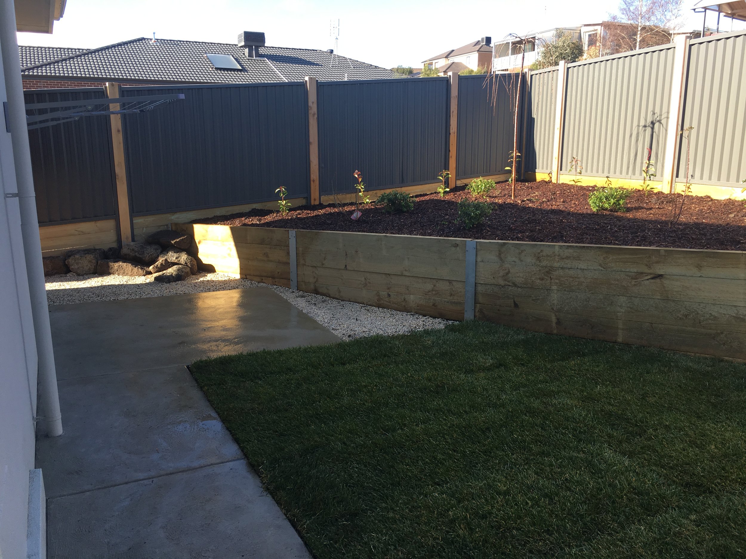 Instant turf, sleeper retaining wall with garden bed, rock area and pebbles