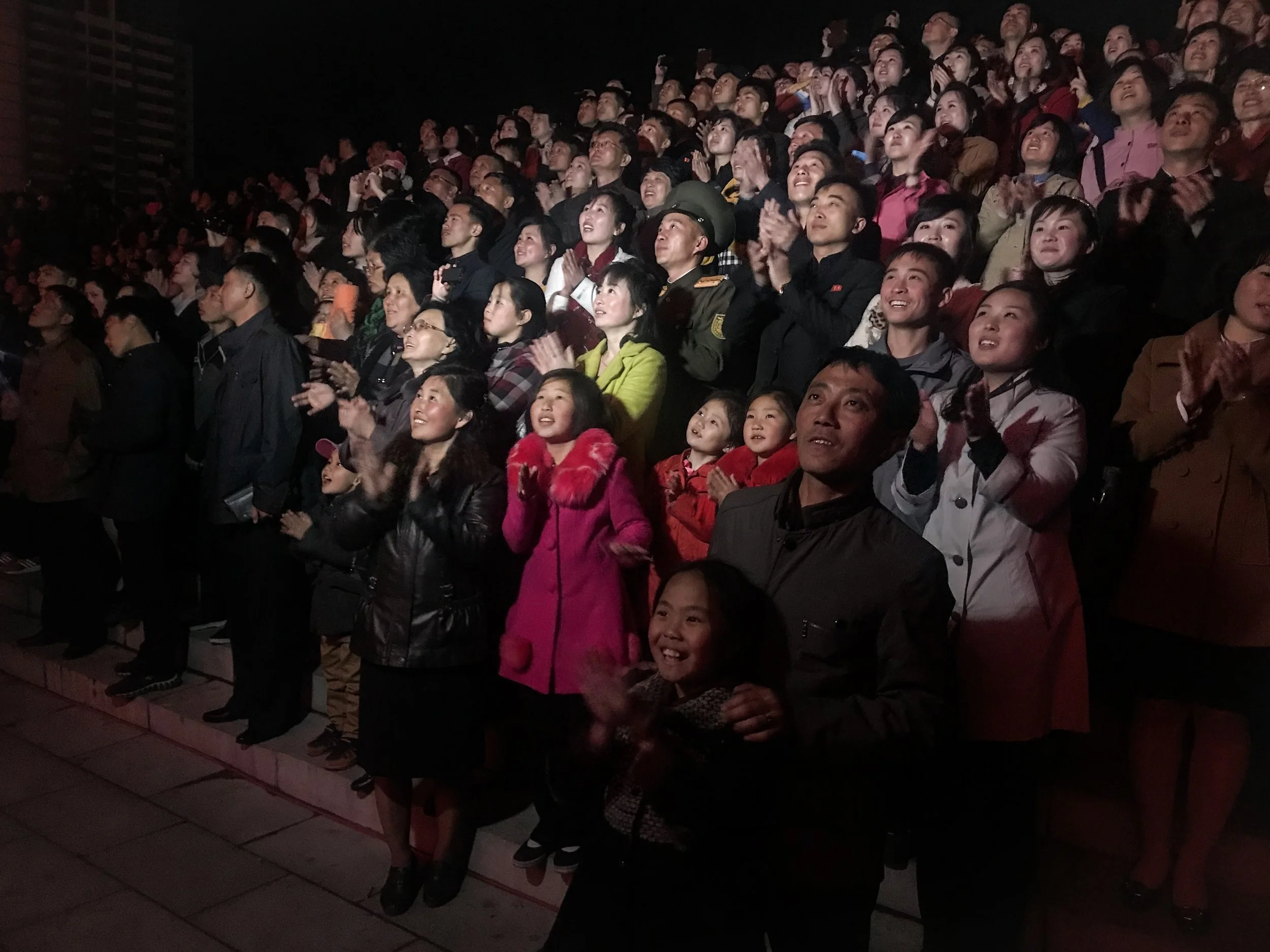 North Koreans take in a fireworks display in the nation's capital Pyongyang to commemorate the Day of the Sun, the birth anniversary of former president Kim Il-sung. As I watched the fireworks I noticed a local film crew shining a light into the cro…