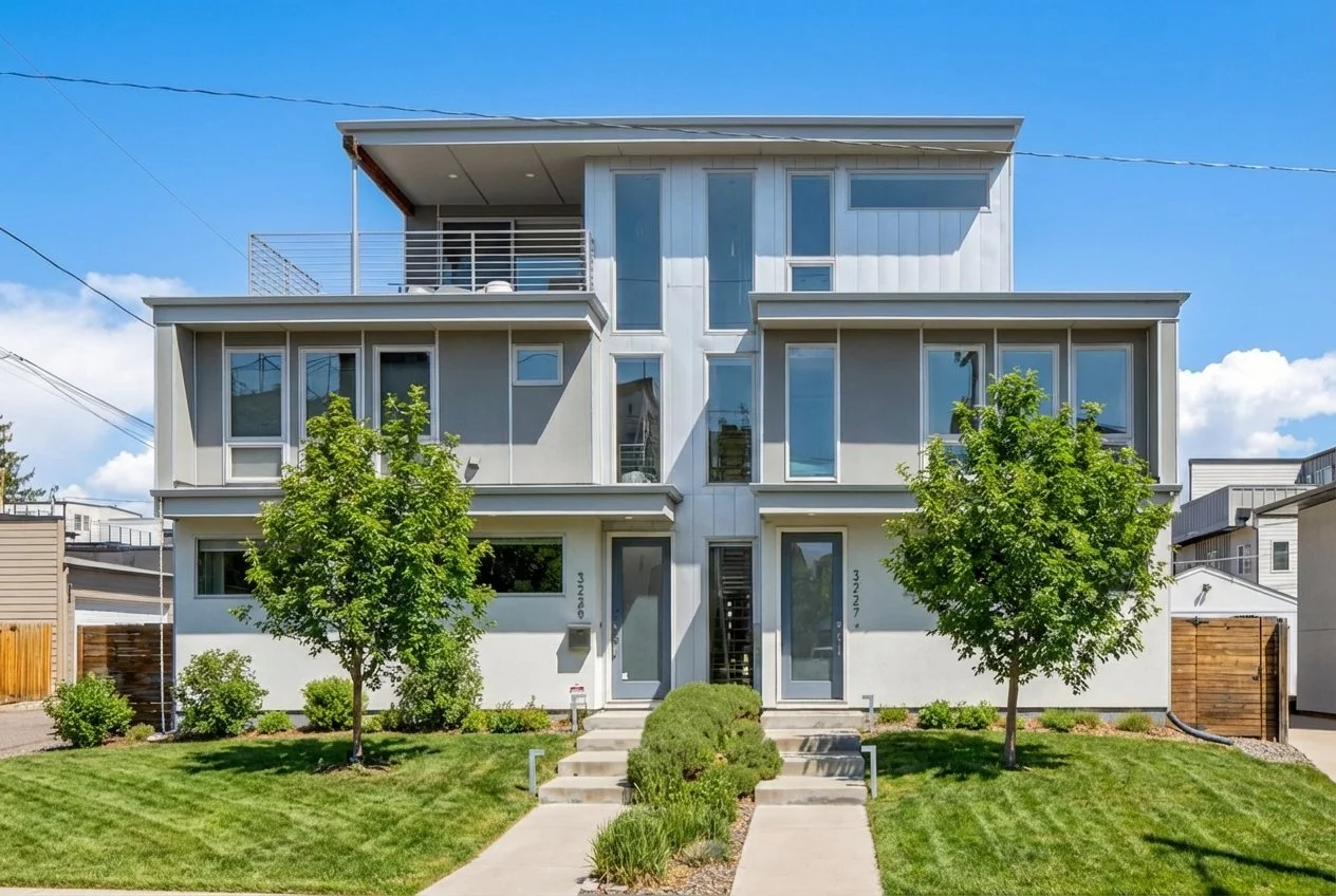 Modern multi-family residential building with three floors, large windows, and a well-maintained lawn with two trees in front.