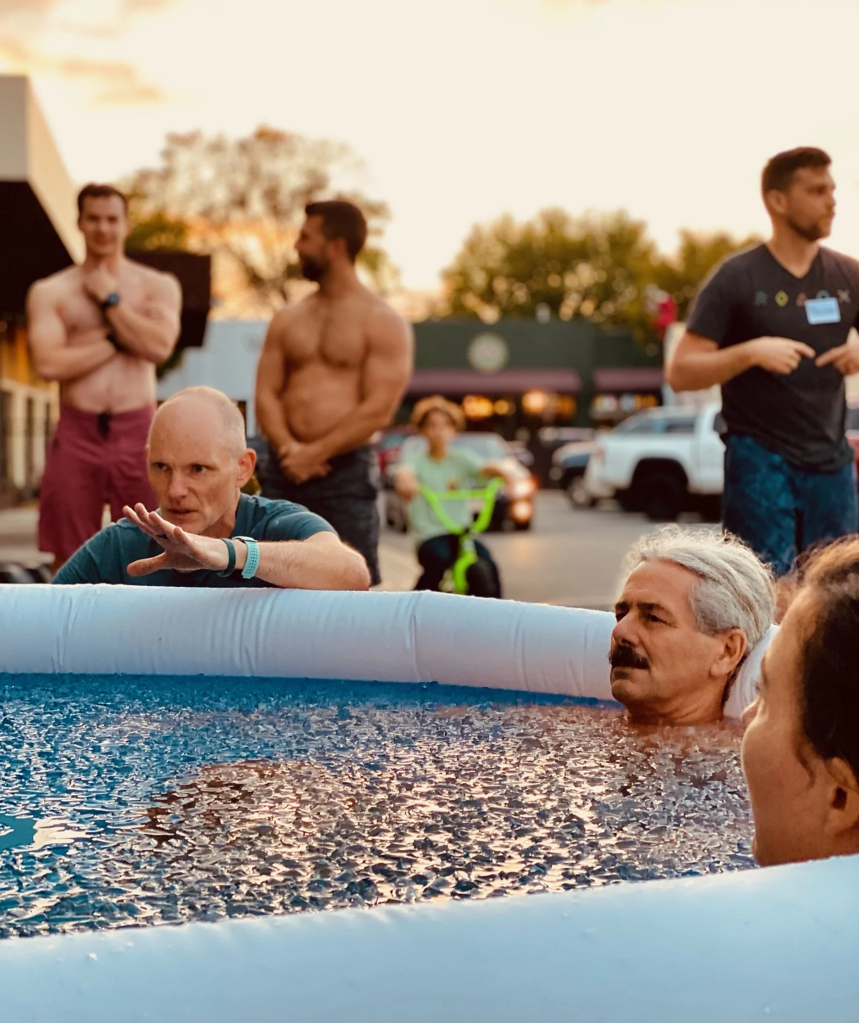 A man giving a lecture to two women in a gym, with a presentation slide about diaphragm mechanics displayed on a large screen.