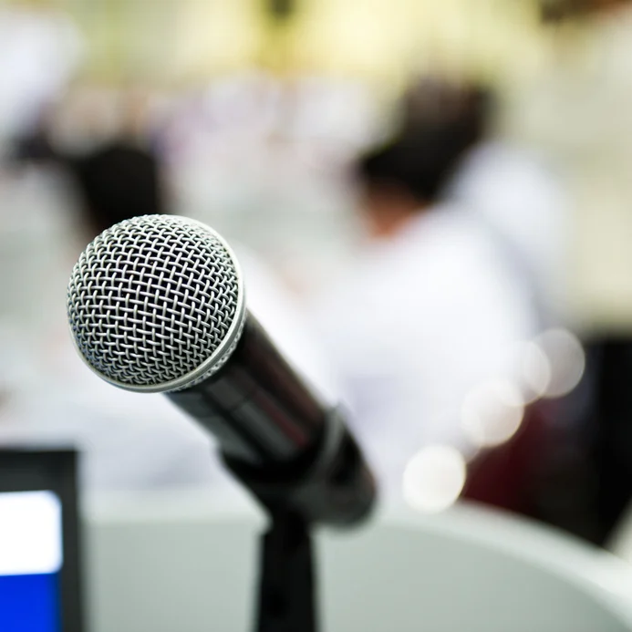 Closeup microphone in conference room with blur person.