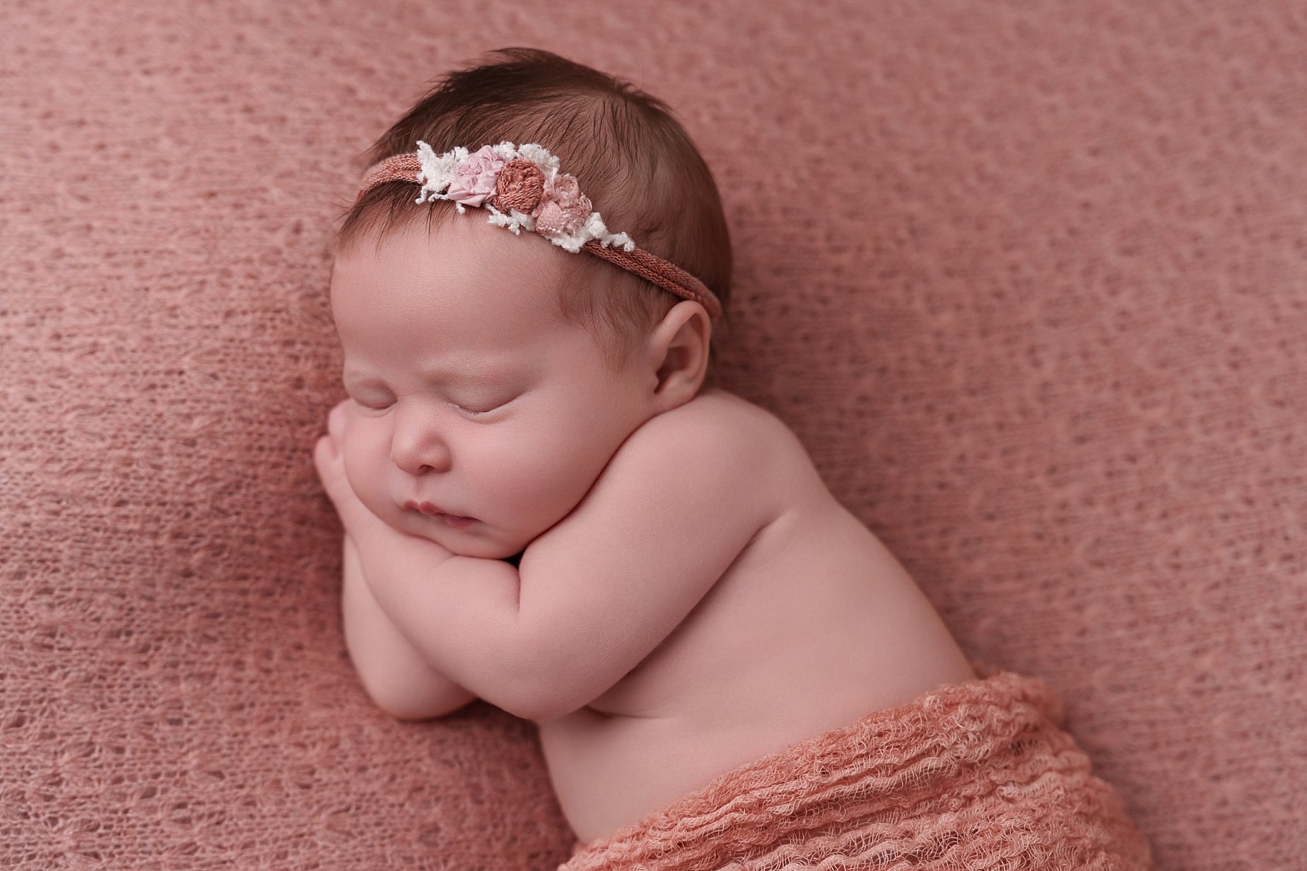 Baby girl posed on a dusty pink backdrop with floral headband at Glen Carbon IL newborn photography studio