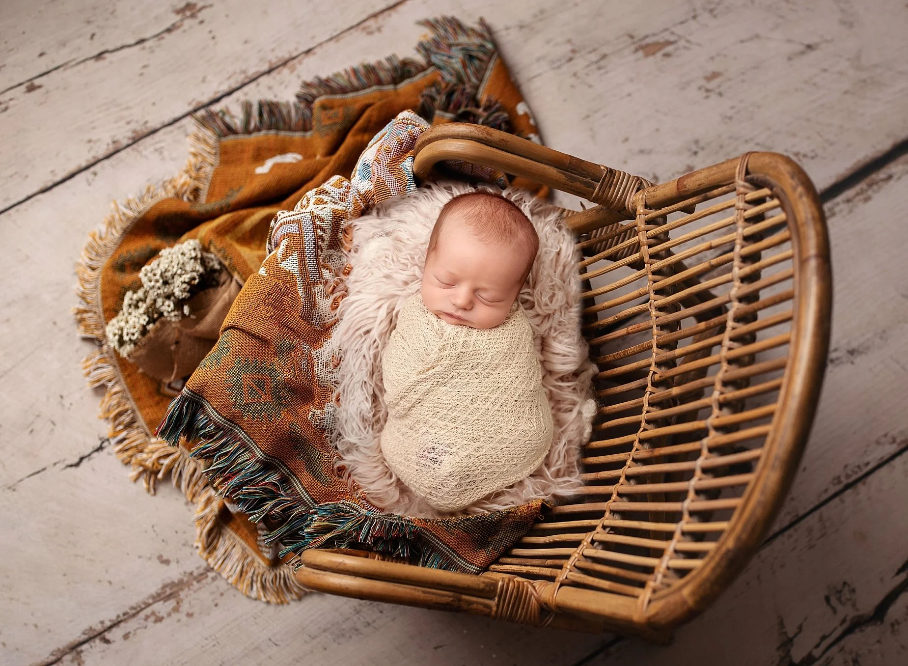 Newborn baby wrapped in cream in a rustic basket at Conner James Photography, a newborn photographer serving Edwardsville and Glen Carbon, IL.
