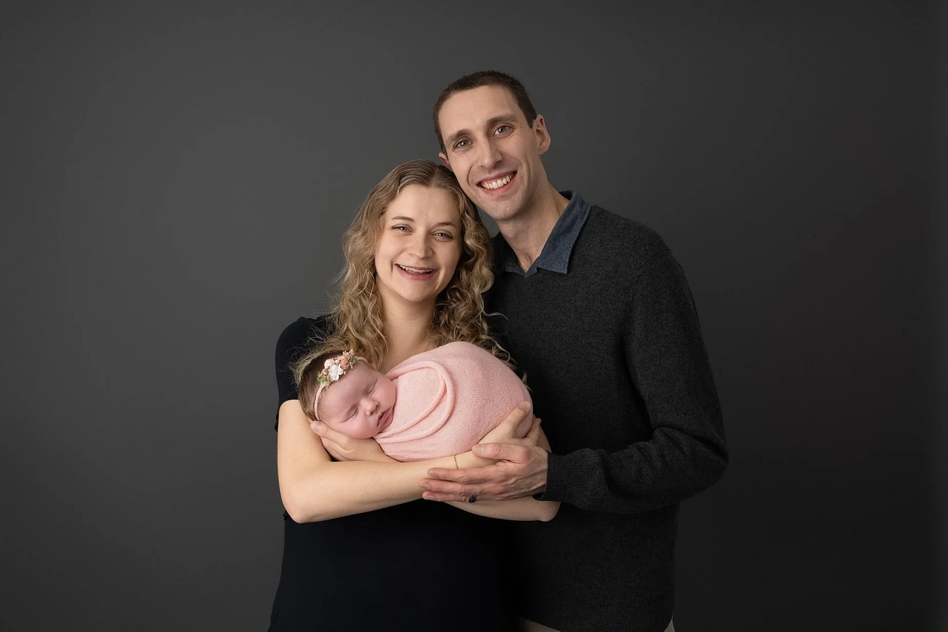 Parents holding wrapped newborn baby girl during professional newborn photography session in Edwardsville IL.