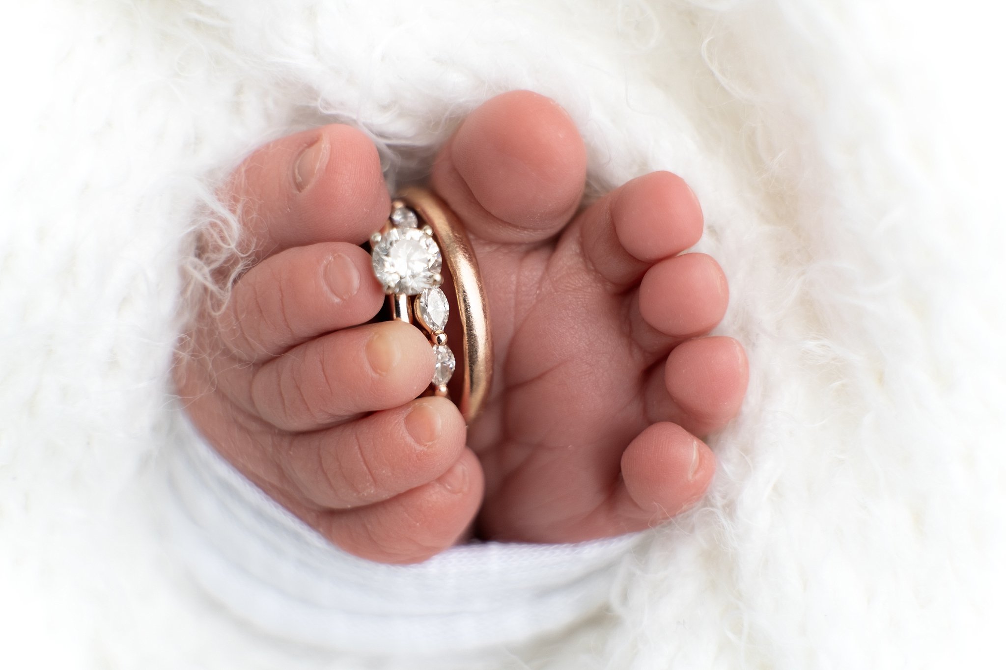 Close-up newborn detail photo holding parents wedding rings in Glen Carbon, Illinois