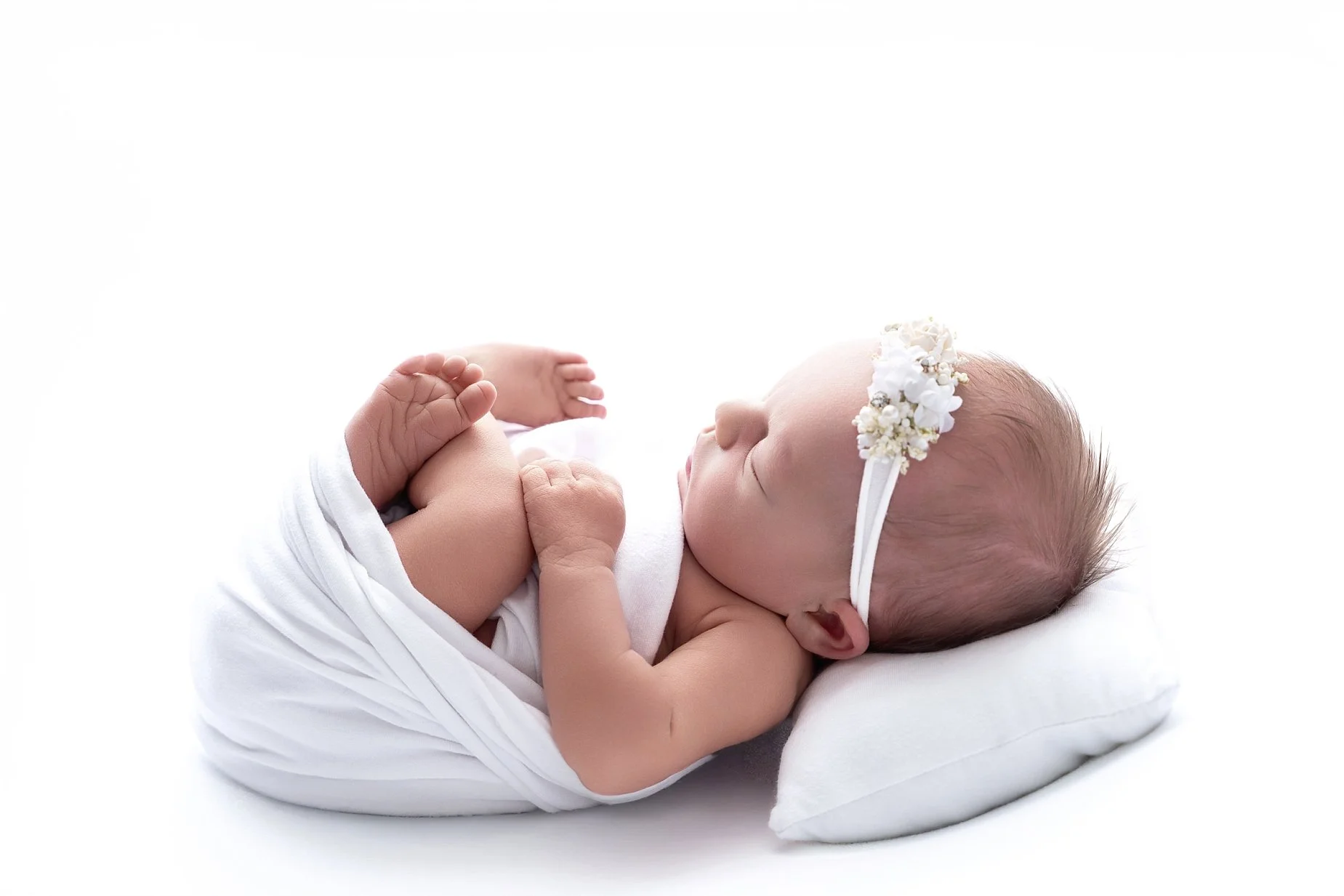 Wrapped newborn baby girl sleeping on a white backdrop photographed by Glen Carbon newborn photographer.