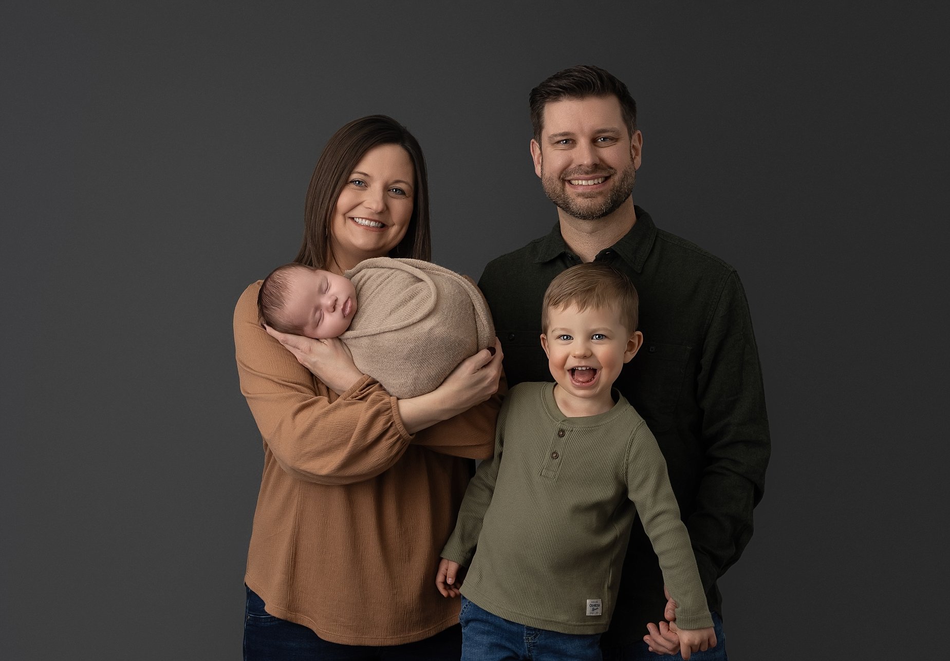 Family newborn portrait with parents holding baby and toddler smiling in studio session Glen Carbon IL.