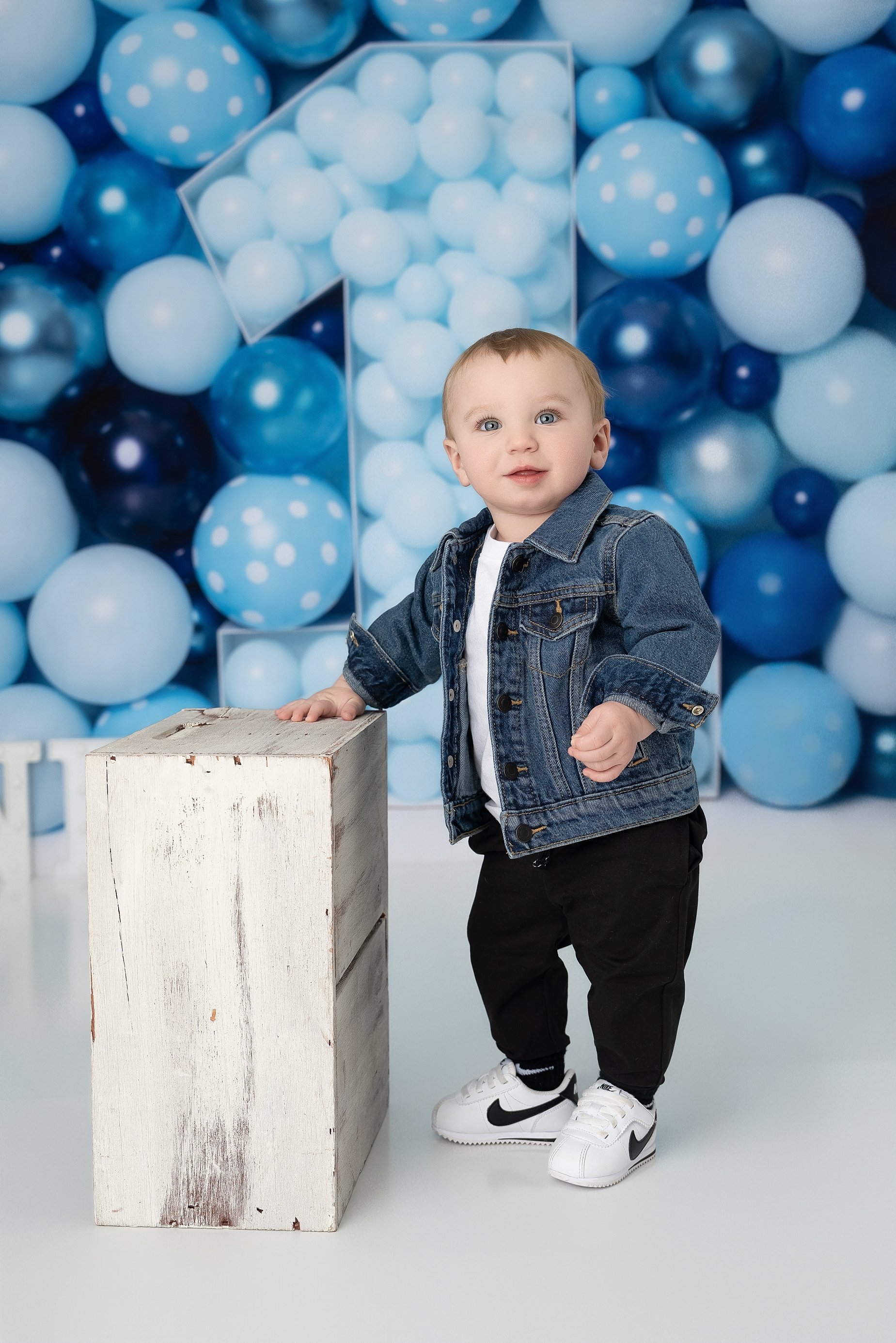 One year old baby boy standing in blue balloon setup milestone session Glen Carbon IL.
