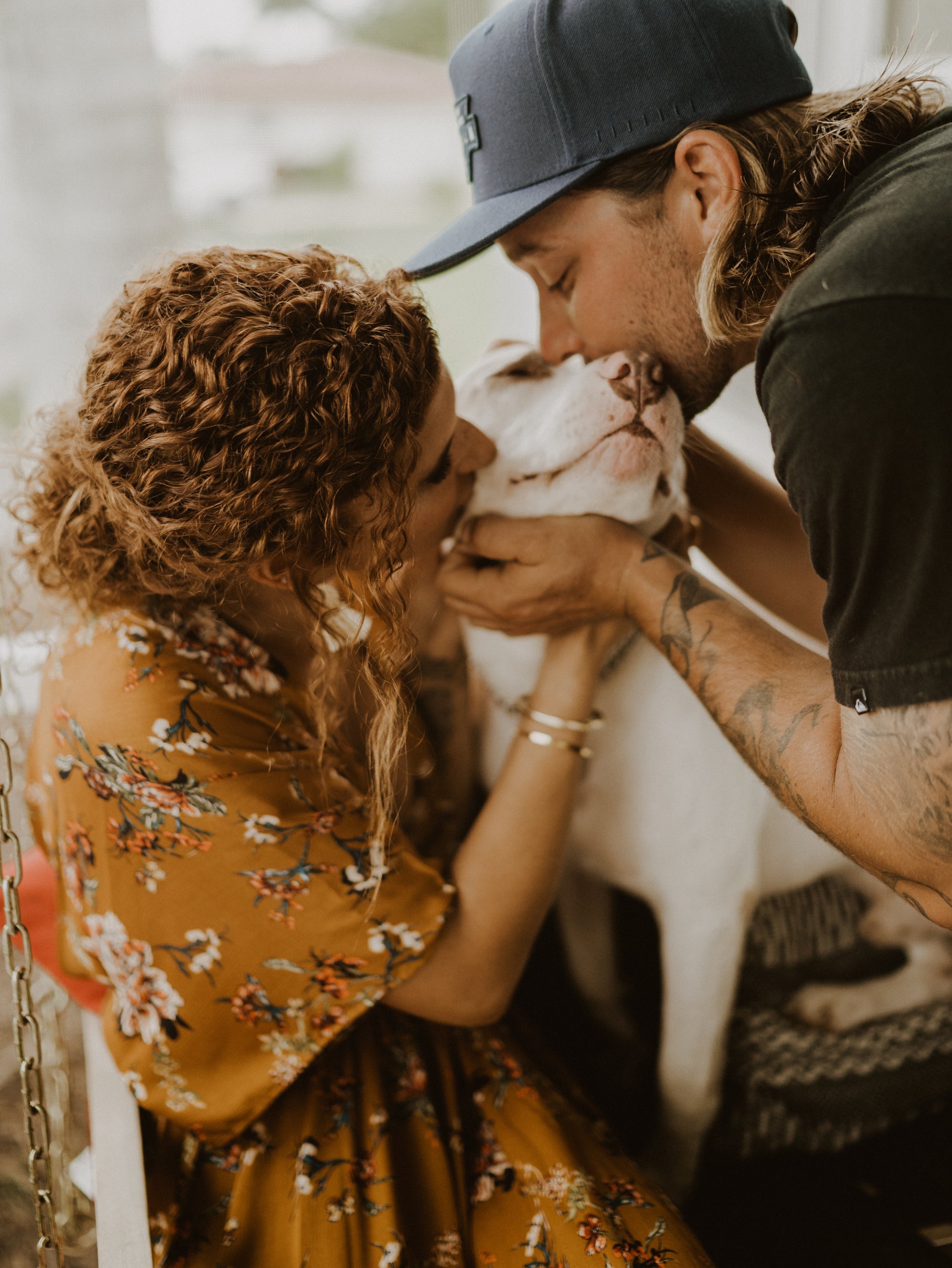 couple kissing dog in home photo shoot