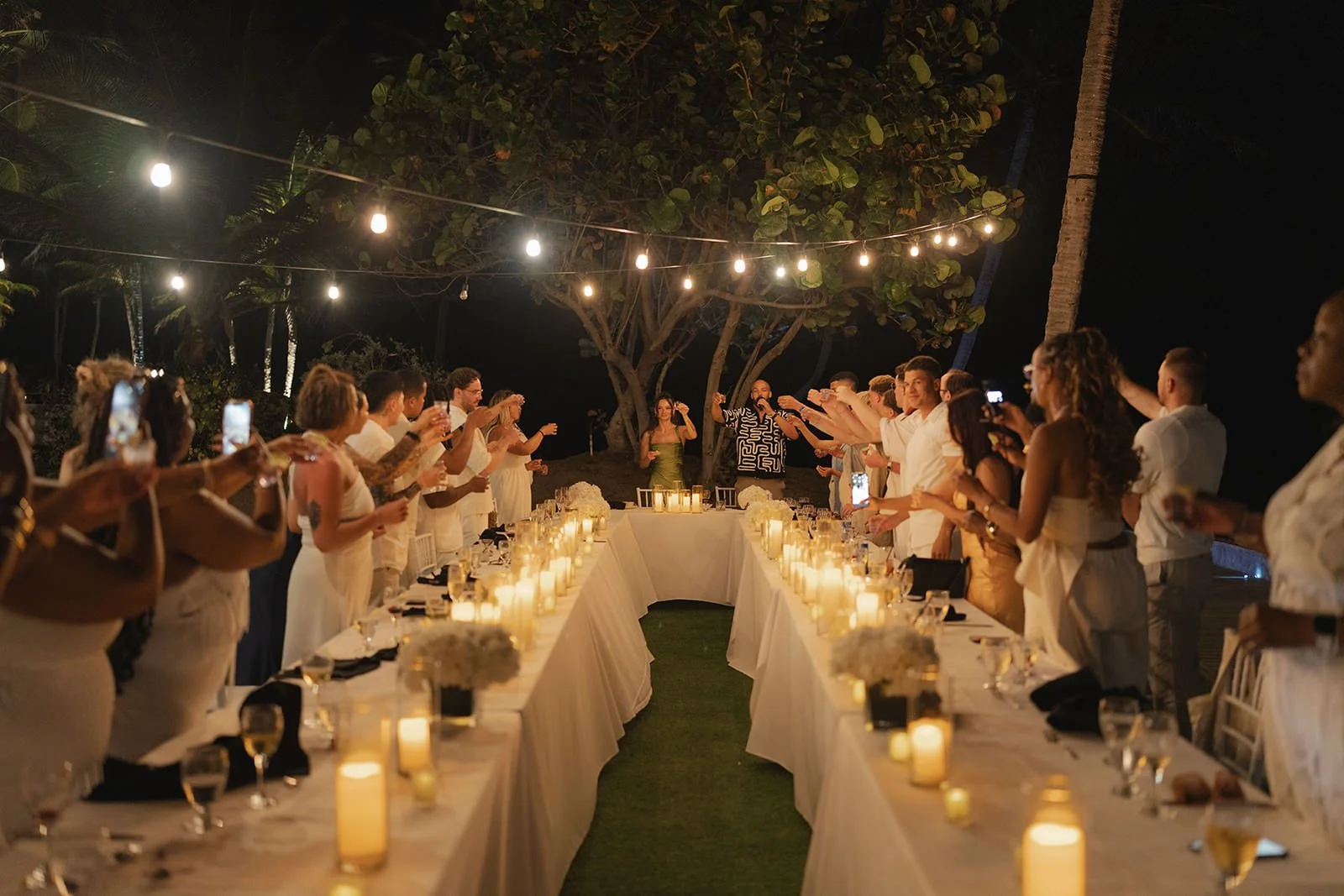Reception tables strung with string lights at the St. Lucia welcome dinner, evening view