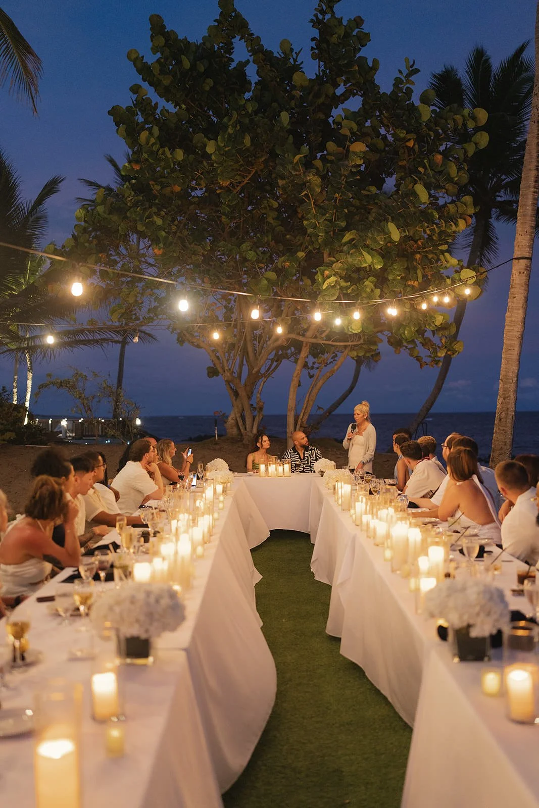 Long dinner table set with white linens and candles at golden hour, St. Lucia welcome dinner