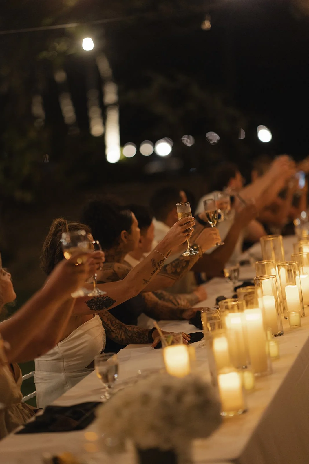 Long candlelit dinner table set for the St. Lucia welcome dinner, glowing at night