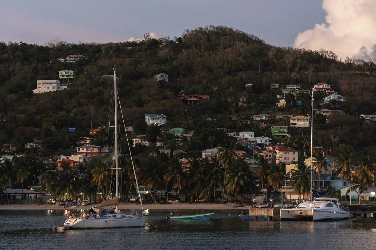 View of a St. Lucia hillside town with colorful houses along the coastline, seen from the catamaran during the wedding weekend sailing excursion