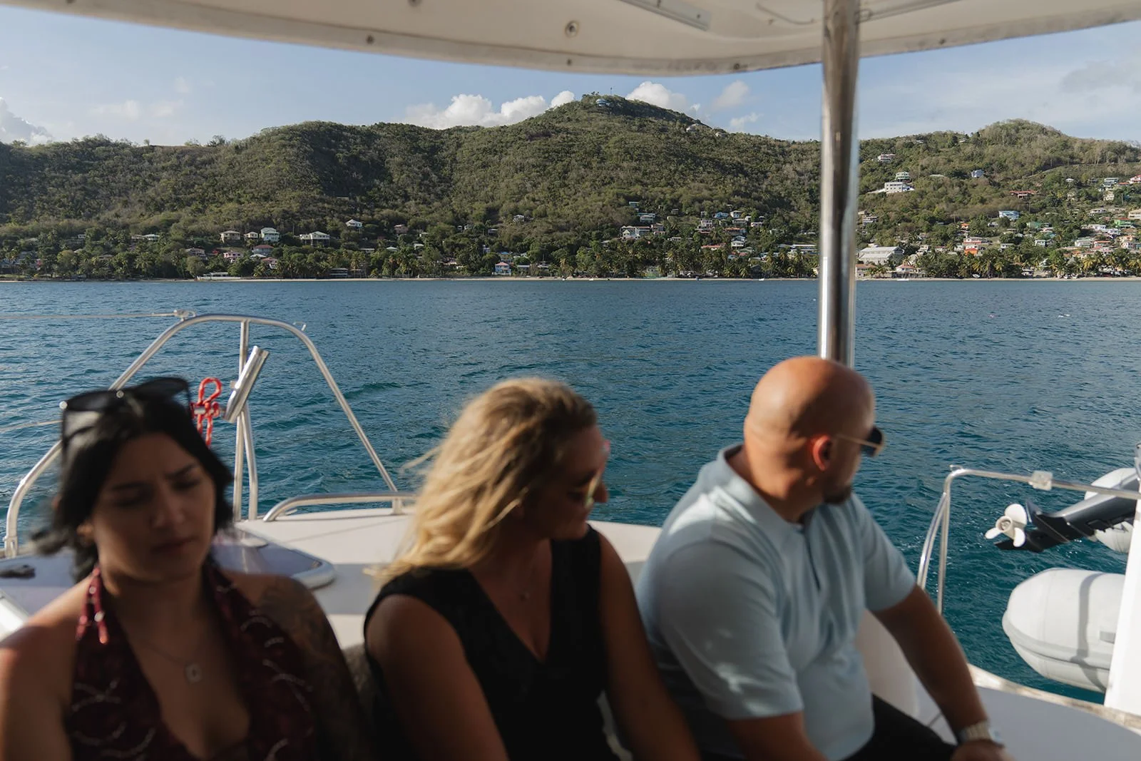 Wedding guests seated on the catamaran under its canopy, green St. Lucia hillsides and coastline visible across the water