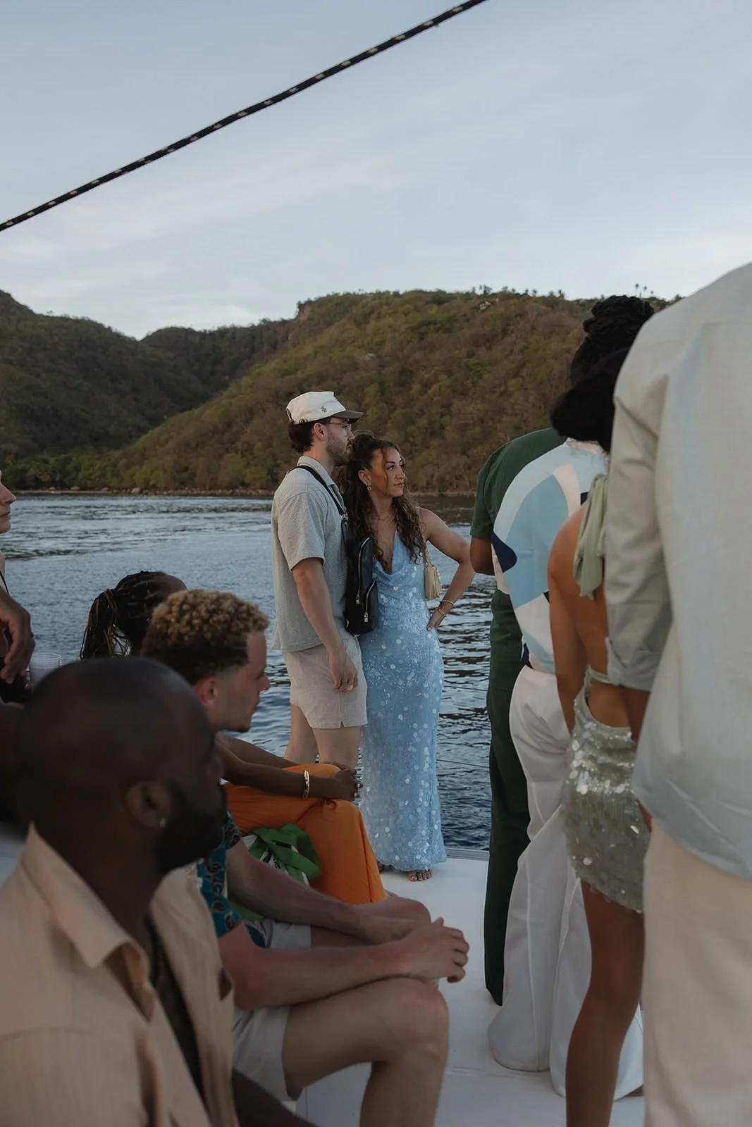 Wedding guests gathered together on the catamaran deck, St. Lucia's green coastline in the background during the sailing excursion