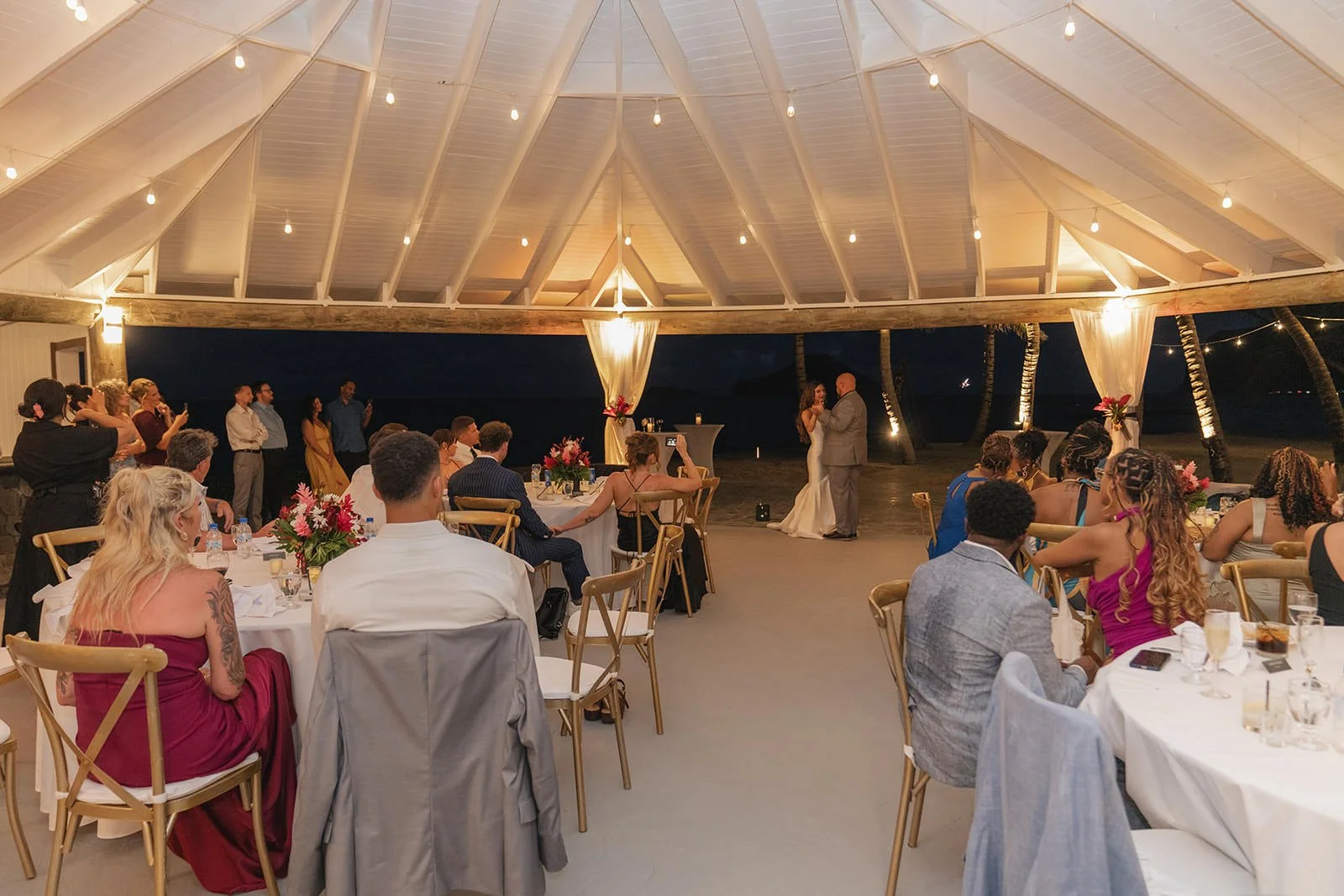 Wedding guests seated at tables during the reception under a lit open-air pavilion in St. Lucia