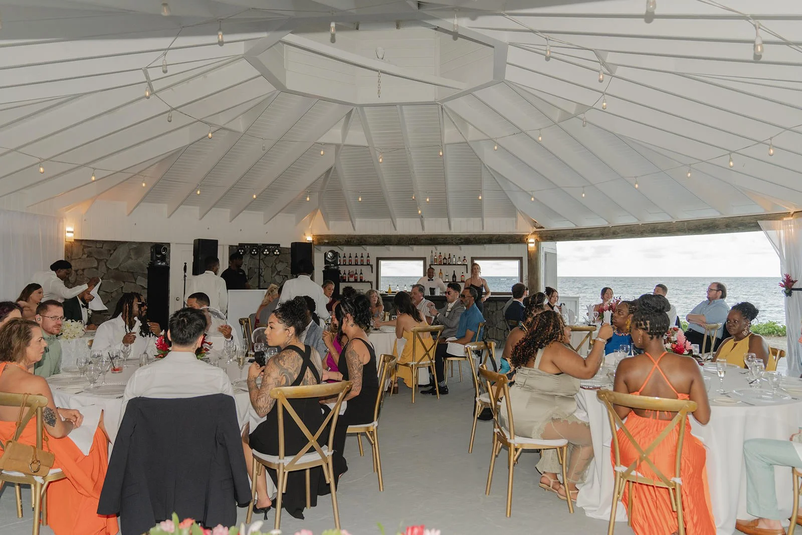 Wedding guests seated at tables inside the palm-thatched reception pavilion at the St. Lucia wedding