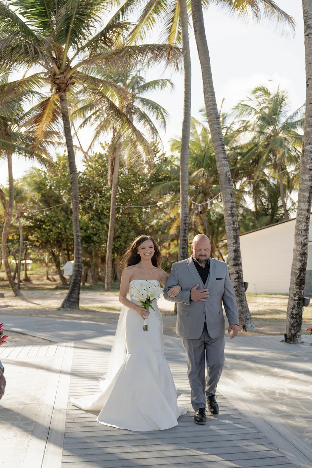 Bride walking along a palm-lined path on the St. Lucia beach during the wedding weekend