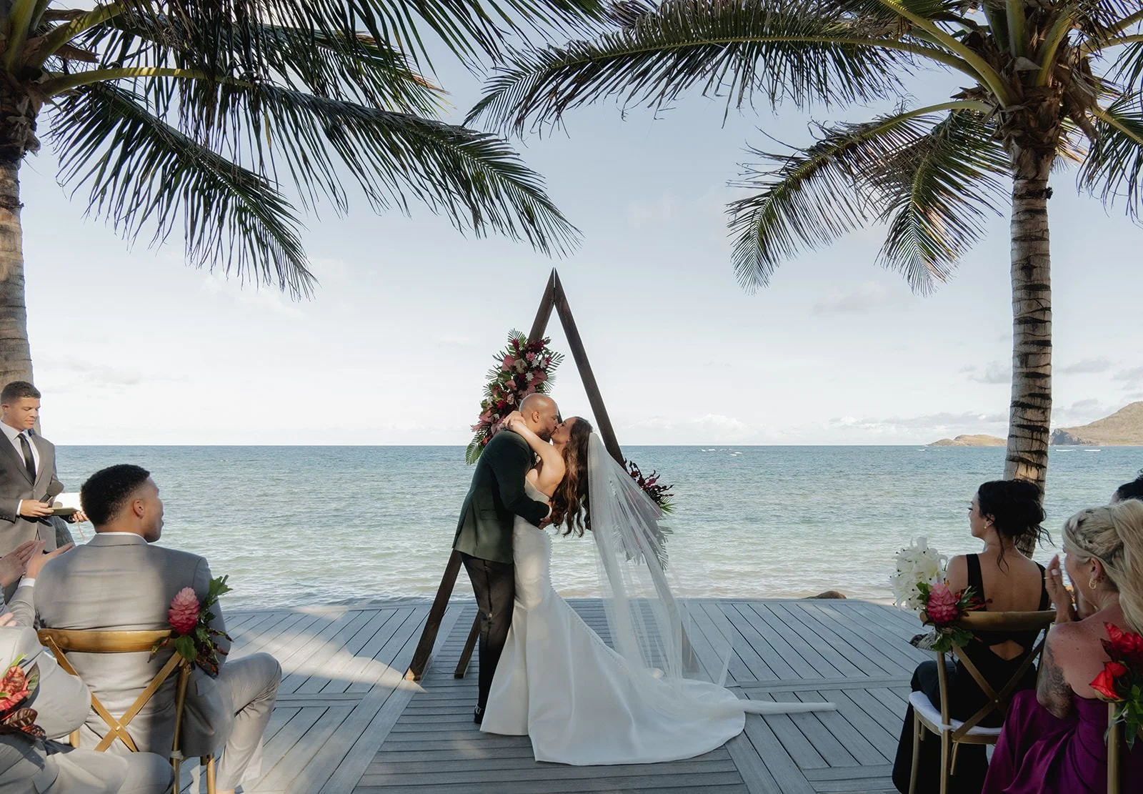 Bride walking down the aisle toward a wooden triangular ceremony arch decorated with florals, ocean backdrop at the St. Lucia wedding ceremony
