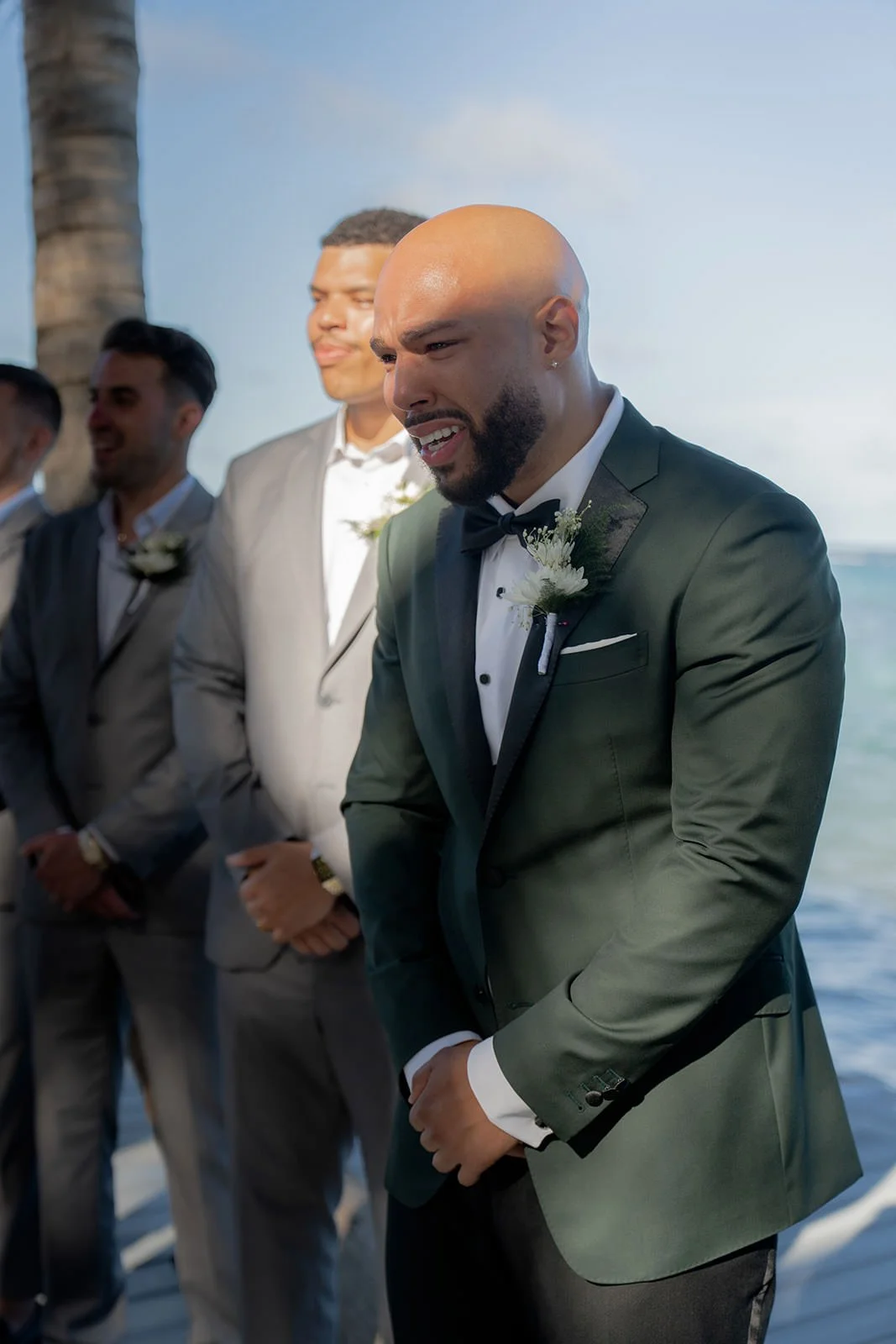 Close-up of the groom's hands clasped together in a dark green suit jacket during the St. Lucia wedding ceremony