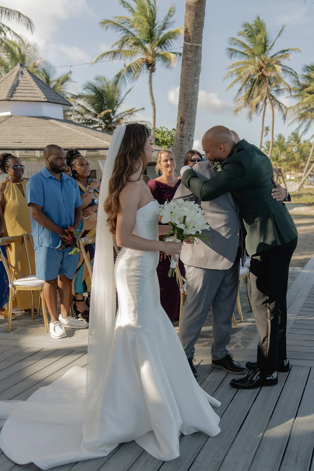 Close-up of the bride's white gown train flowing along the wooden boardwalk during the St. Lucia wedding ceremony