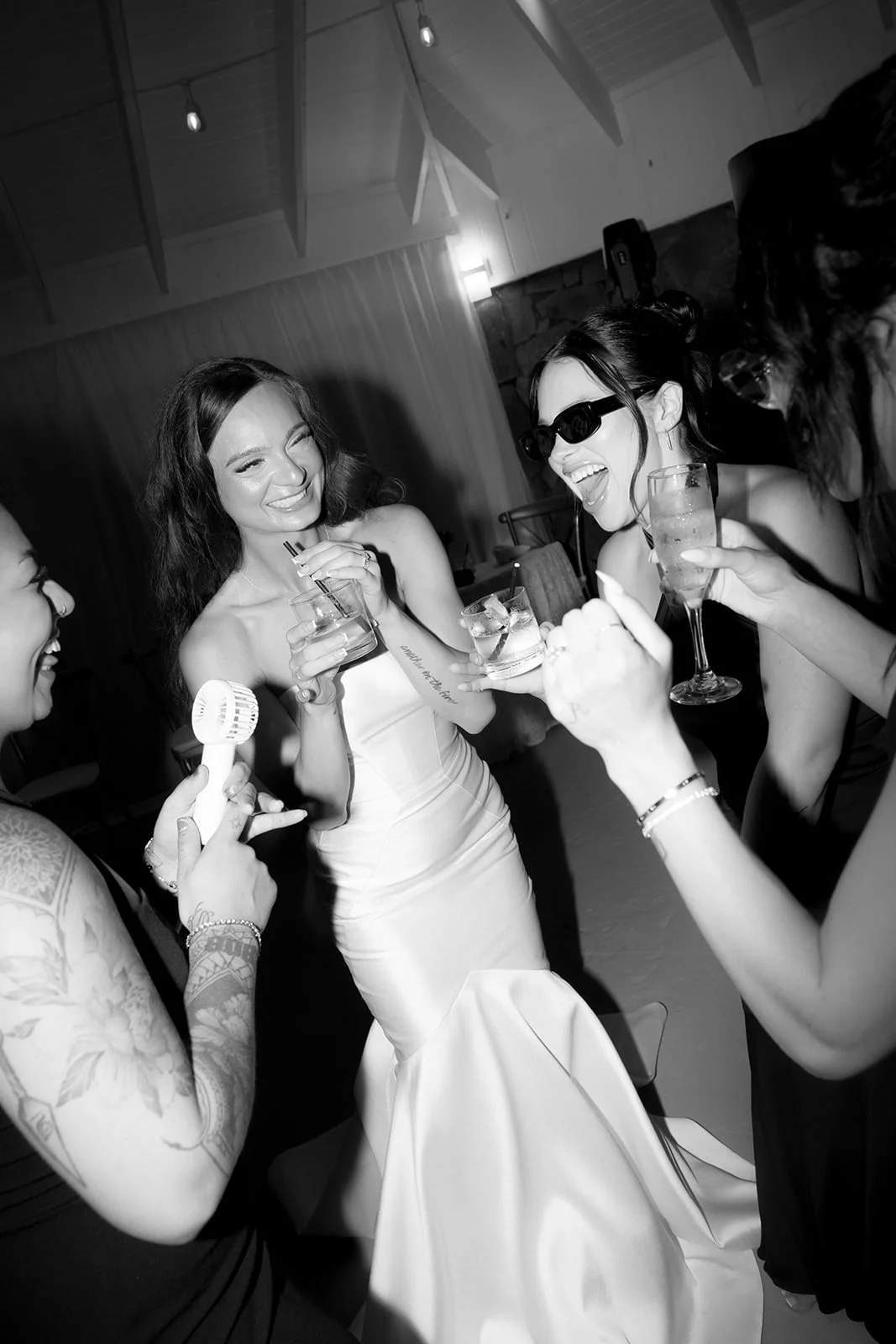 Black and white candid photo of the bride laughing with guests holding champagne glasses at the St. Lucia wedding reception