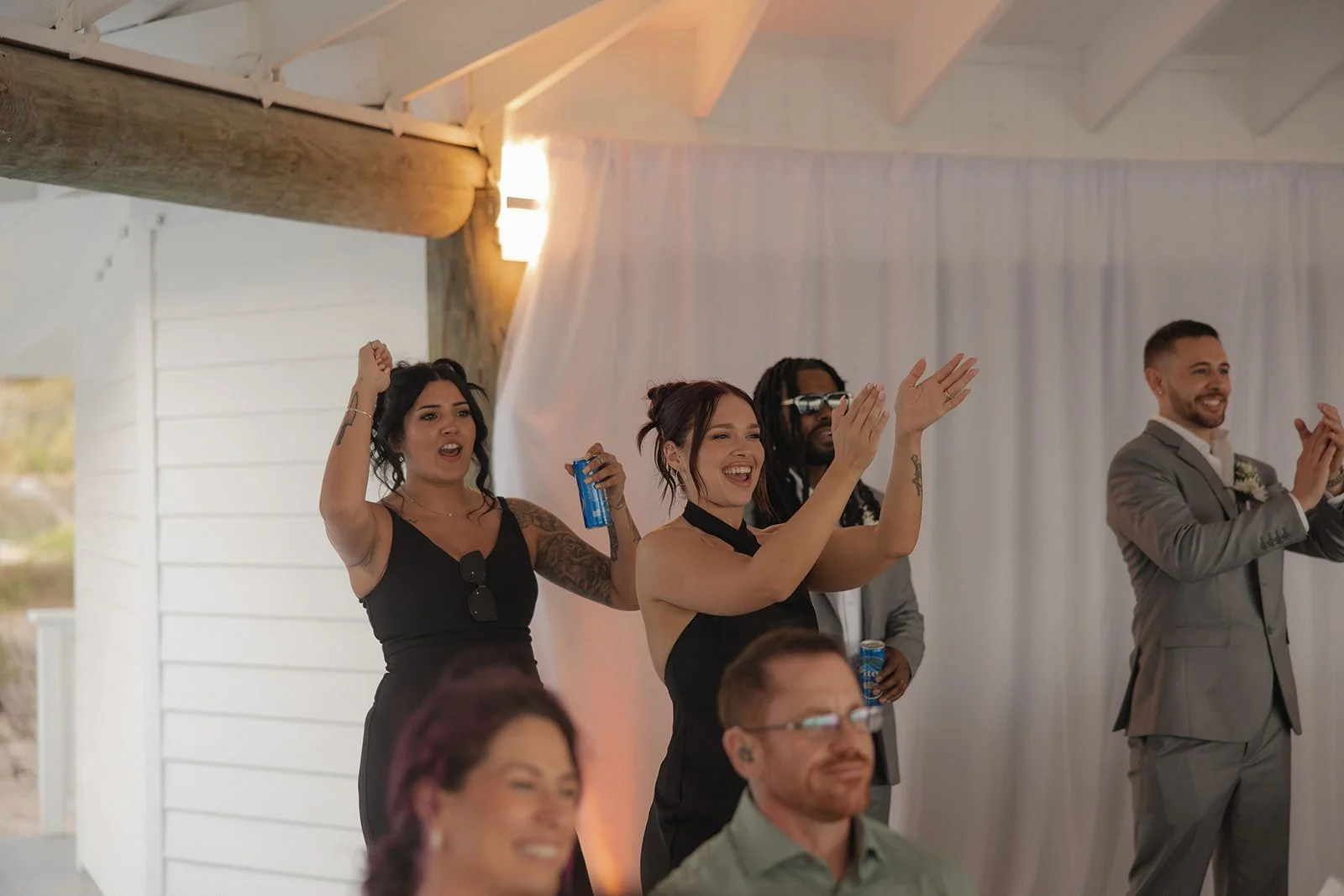 Wedding guests dancing and cheering with hands raised inside the reception tent in St. Lucia