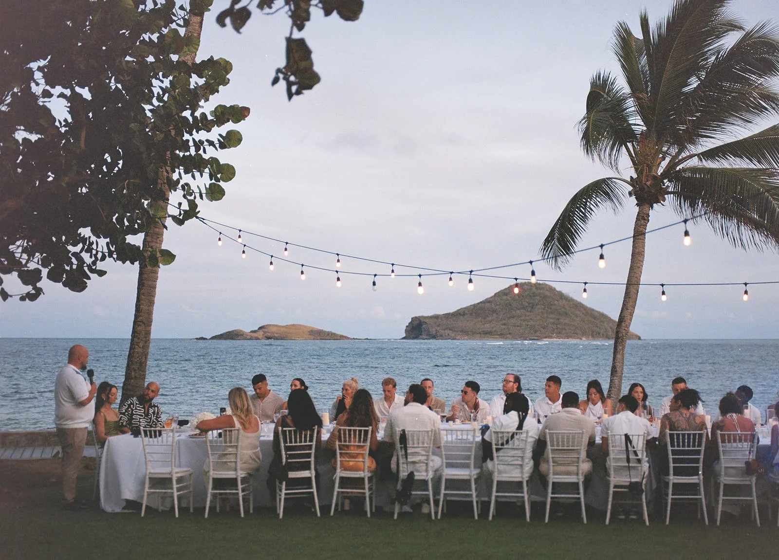 Guests seated at the welcome dinner with wooded hills in the background, St. Lucia wedding