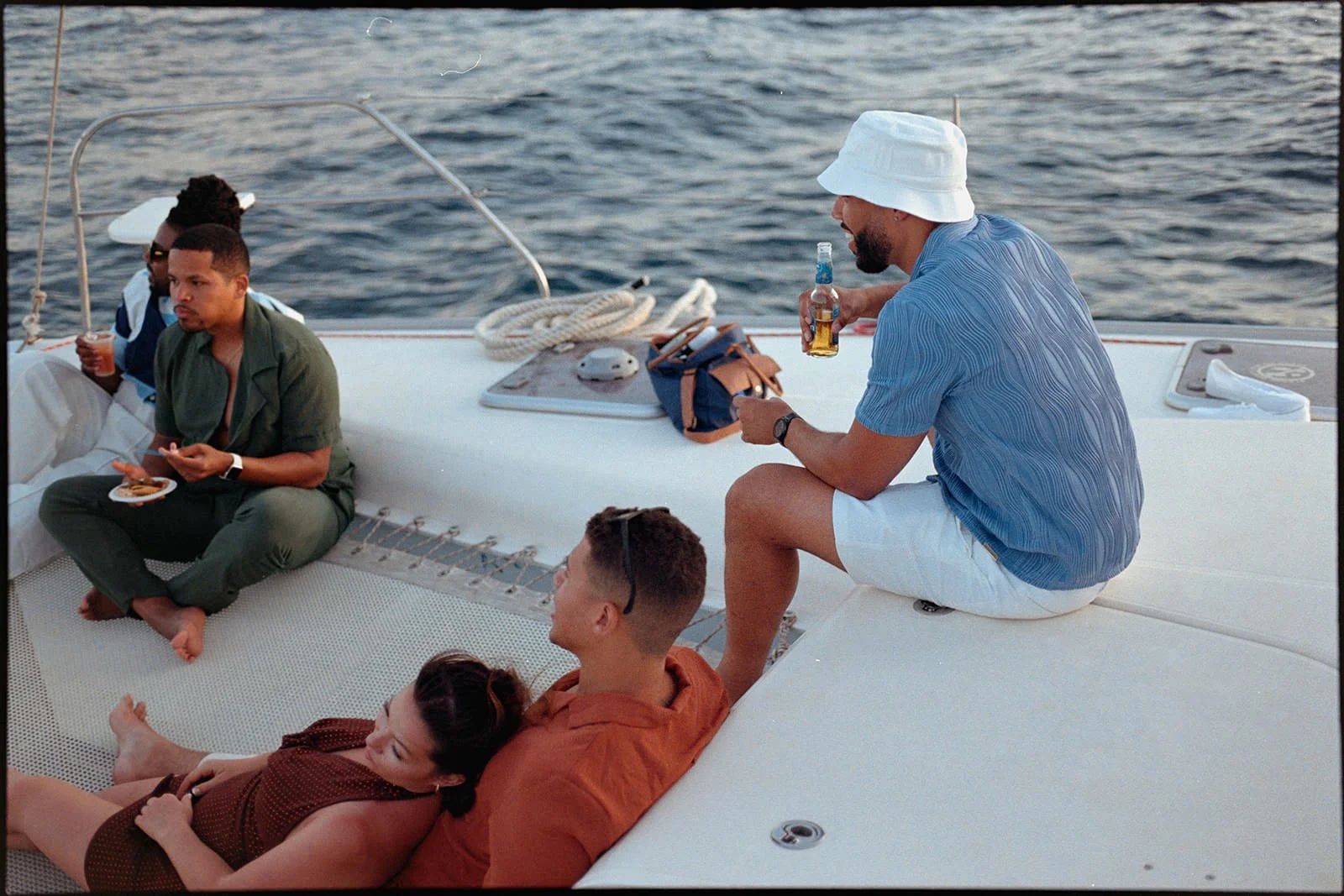 Wedding guests relaxing together on the catamaran's bow, St. Lucia coastline visible behind them during the sailing excursion