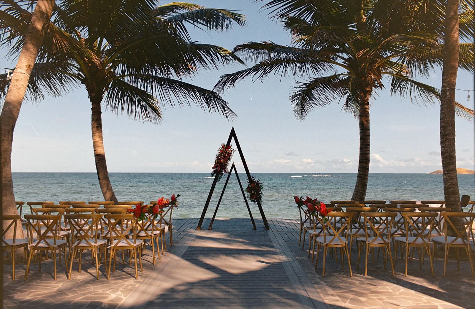 Distant view of the empty St. Lucia beach ceremony arch framed by palm trees before the wedding begins