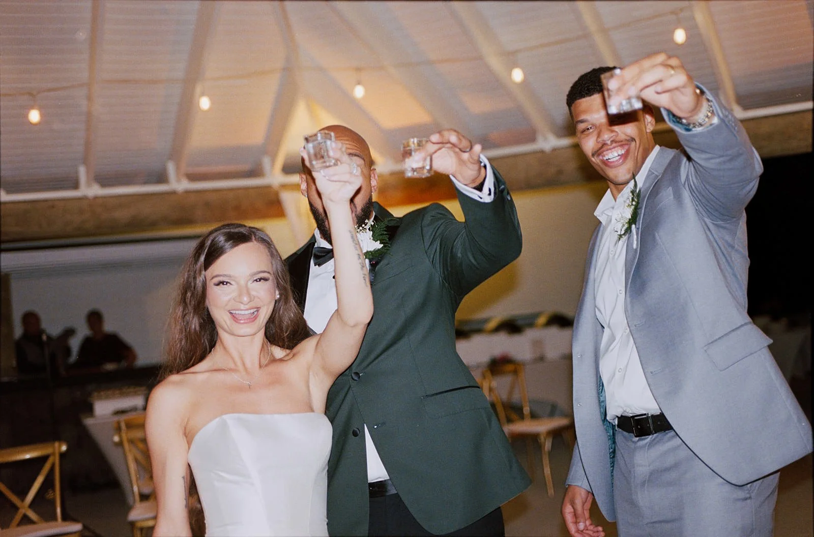 Bride and two groomsmen raising their glasses in a toast inside the St. Lucia reception tent
